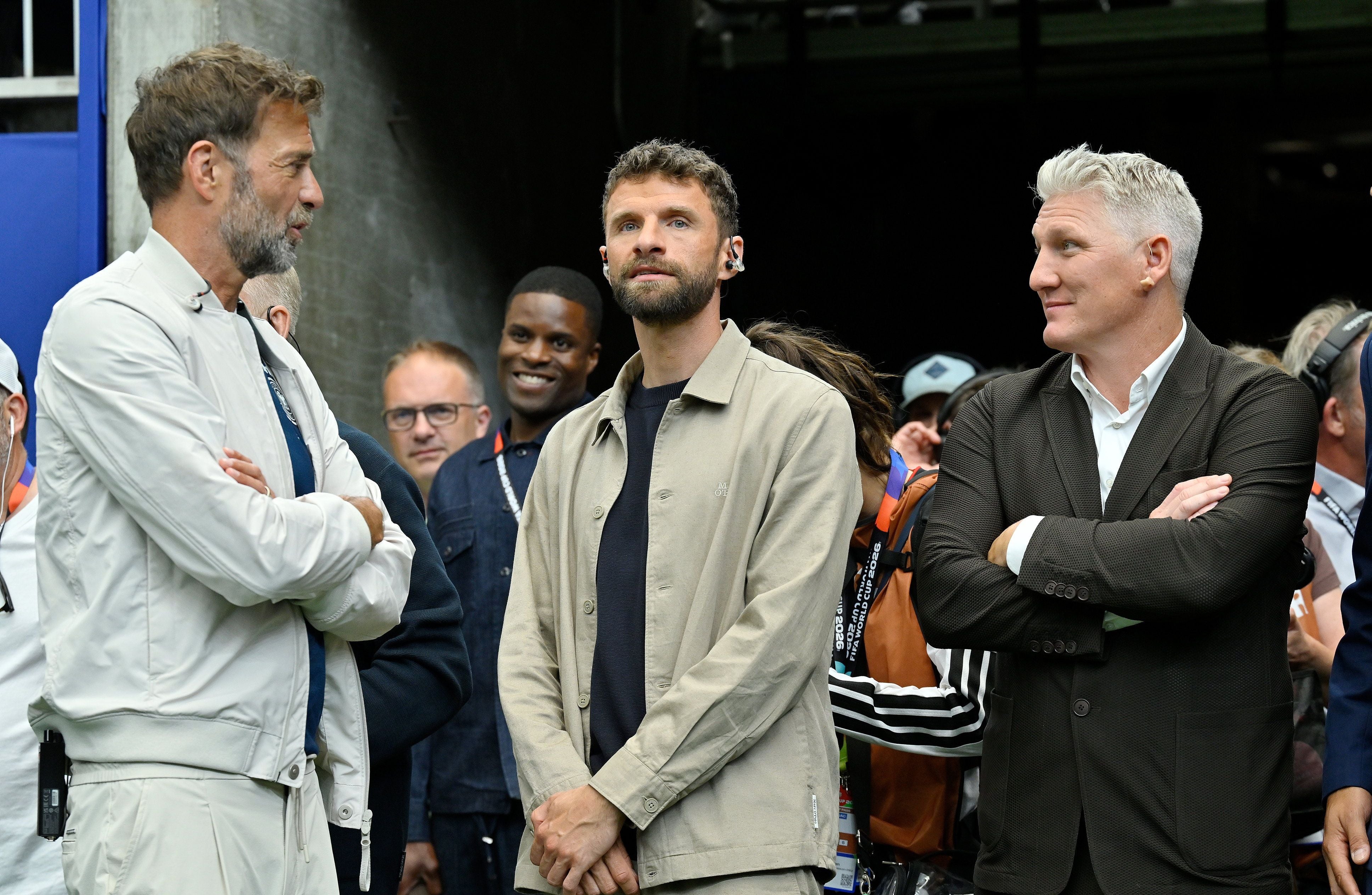 Drei Männer stehen nebeneinander und unterhalten sich bei einer Sportveranstaltung.