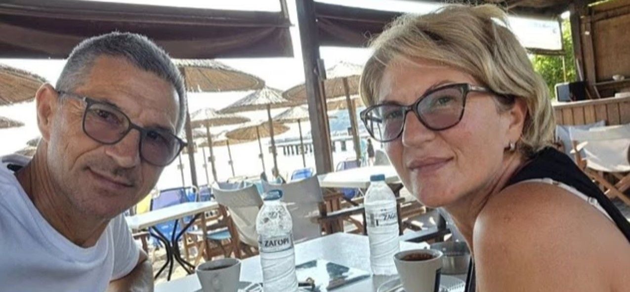 Ein Mann und eine Frau sitzen in einem Strandcafé mit Kaffee und Wasserflaschen auf dem Tisch.