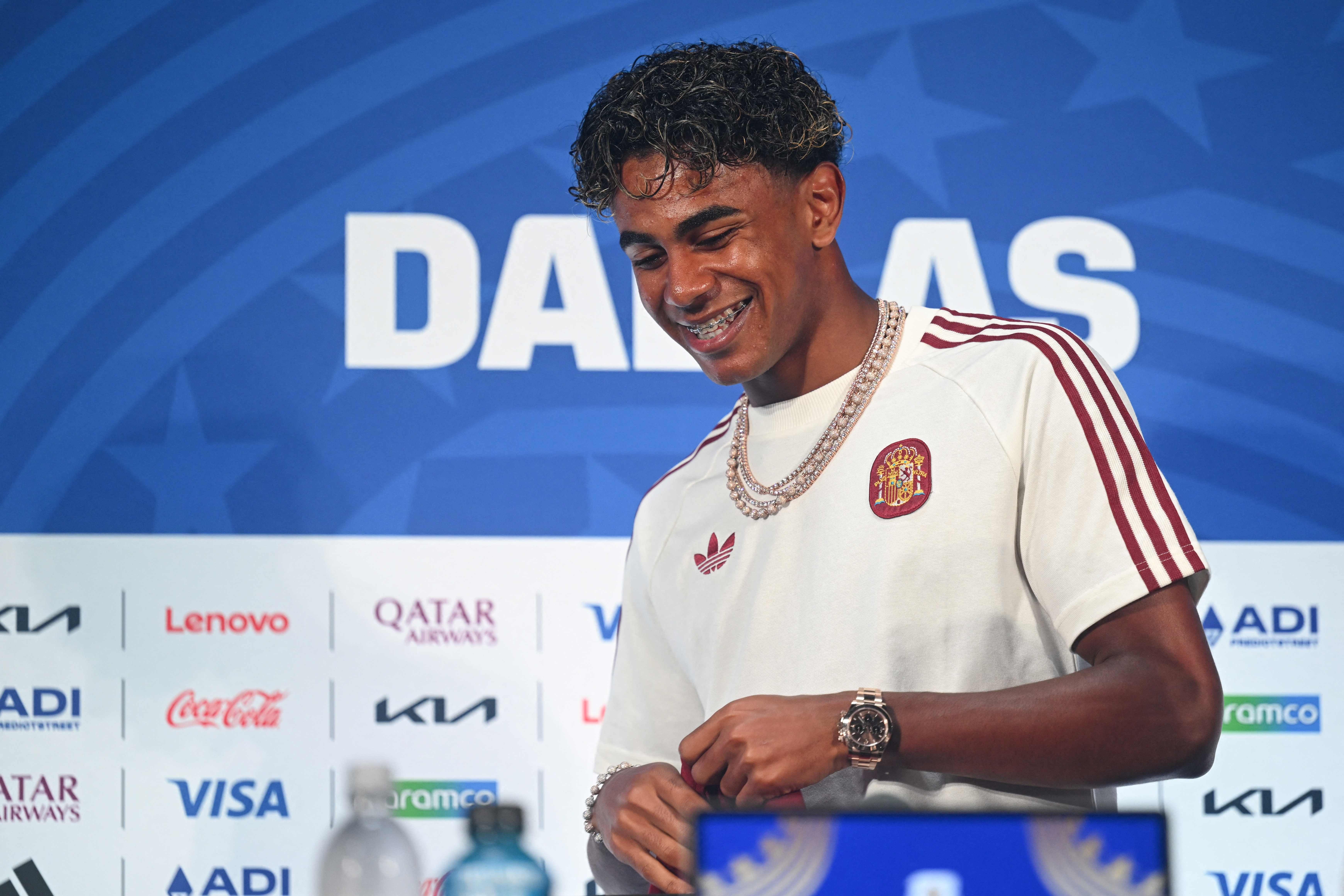 Ein junger Fußballspieler im Spanien-Trikot lächelt bei einer Pressekonferenz im Stadion.