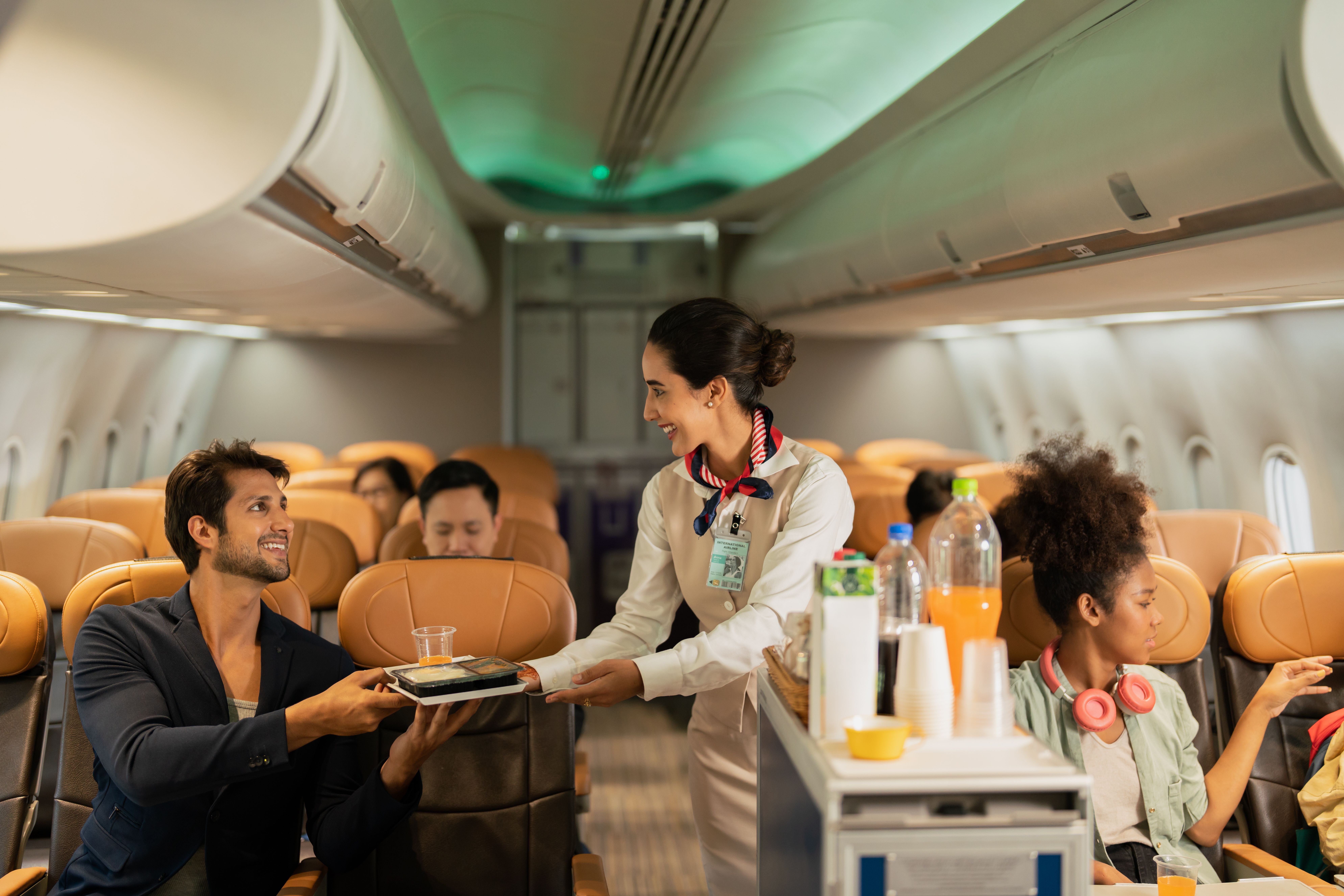 Flugbegleiterin serviert Essen und Getränke Passagieren in der Economy Class eines Flugzeugs.