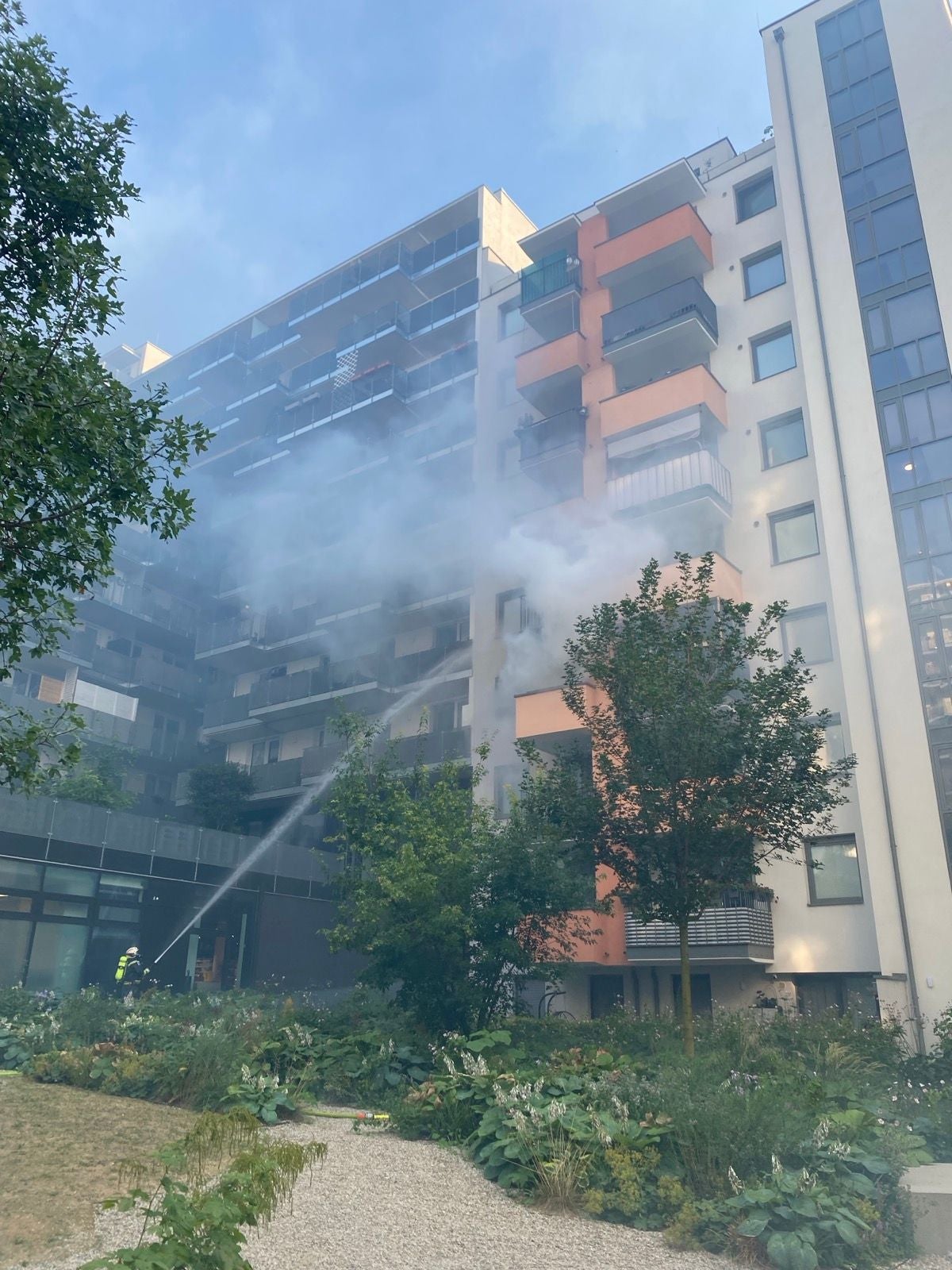 Feuerwehr löscht Zimmerbrand in einem Hochhaus, starker Rauch dringt aus dem Gebäude.