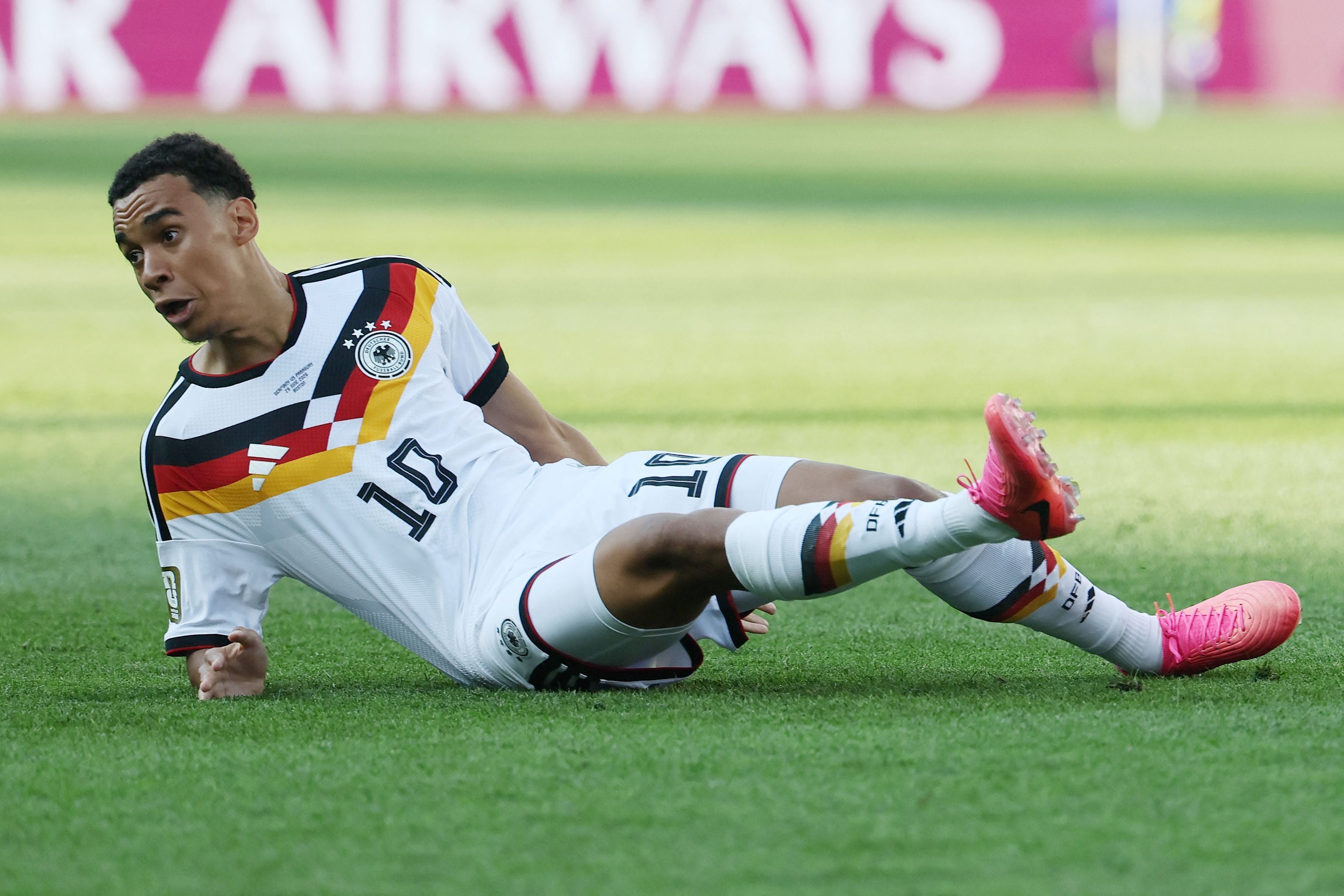 Ein deutscher Fußballspieler im weißen Trikot liegt während eines Spiels auf dem Rasen.