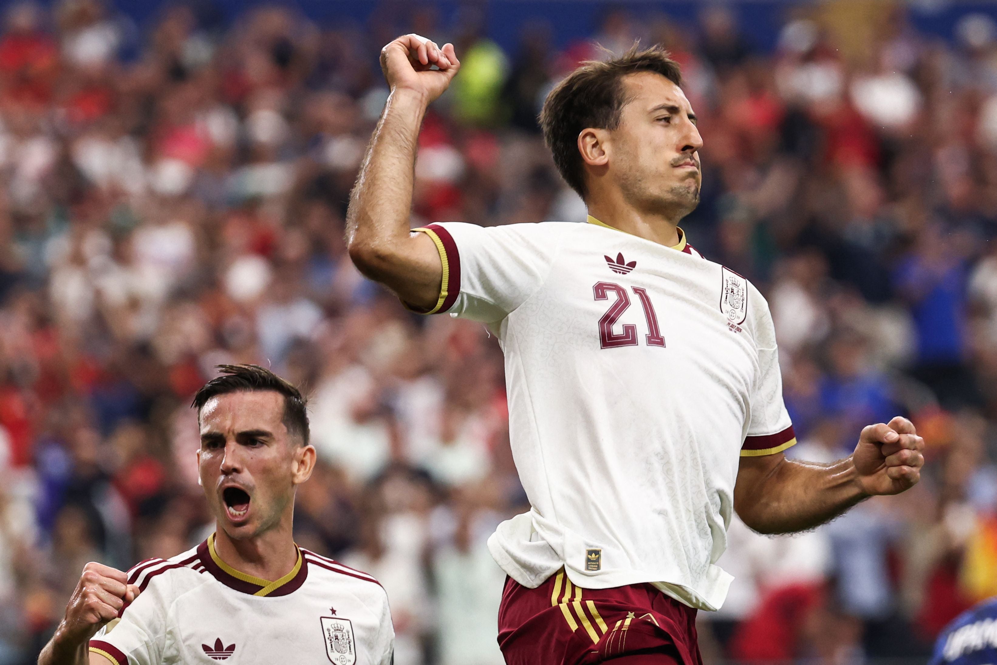 Zwei spanische Fußballspieler jubeln nach einem Tor im Stadion, einer hebt triumphierend den Arm.