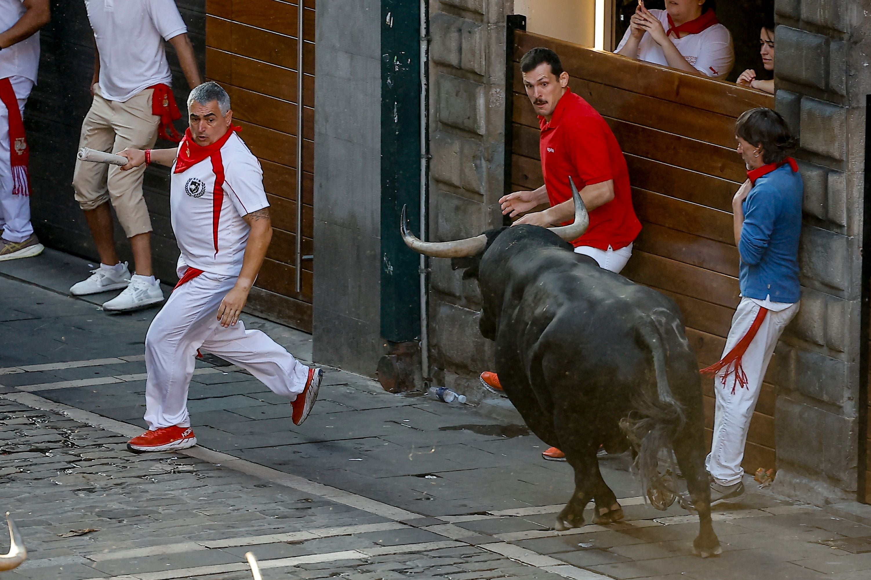 Ein Läufer in Weiß entkommt einem Stier beim San-Fermin-Festival in Pamplona, Spanien.