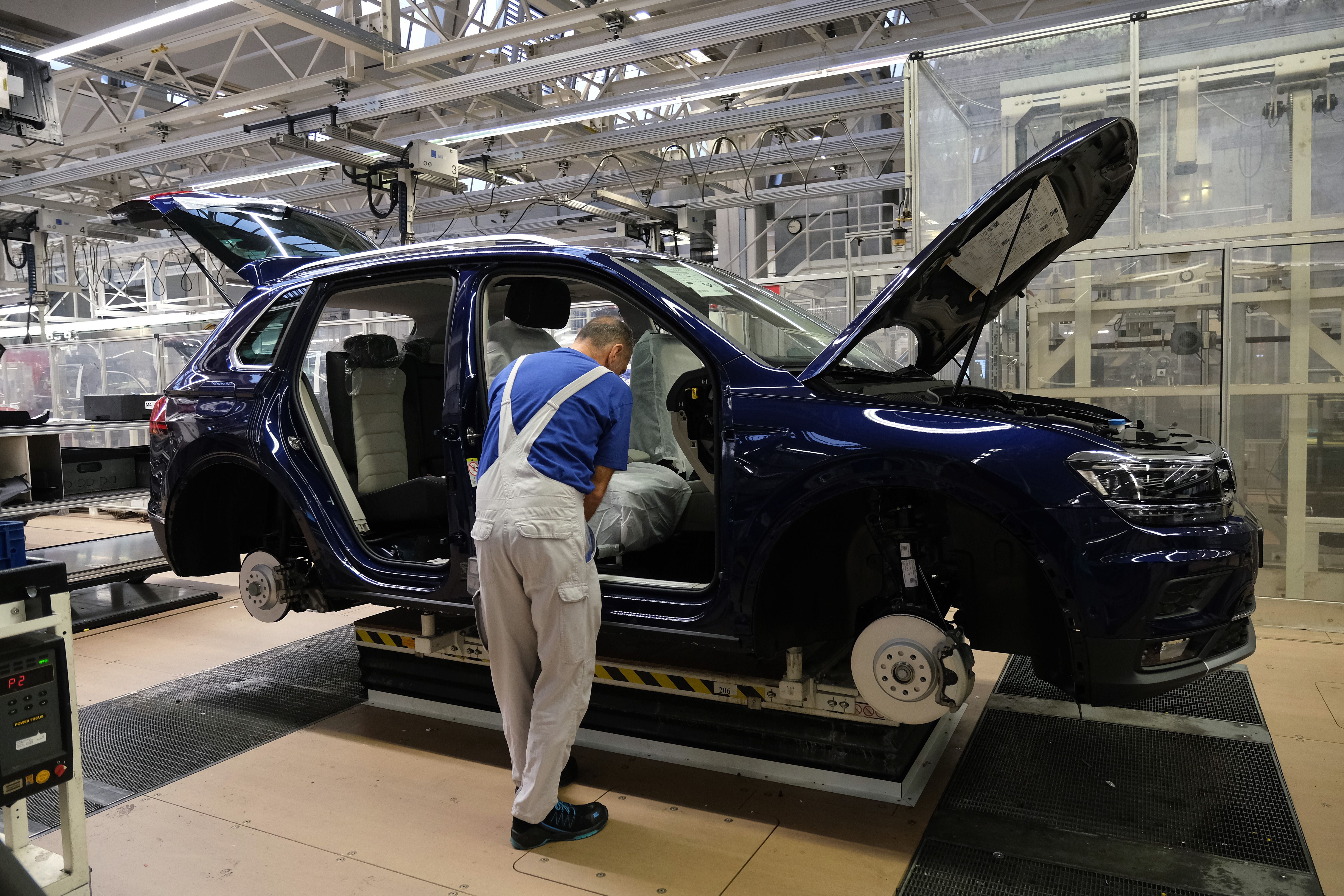 Ein Arbeiter montiert ein Auto an einer Fertigungsstraße in einer Volkswagen-Fabrik.