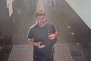 Mann in dunkler Kleidung geht durch einen Flur am Flughafen Wien und hält ein Handy in der Hand.