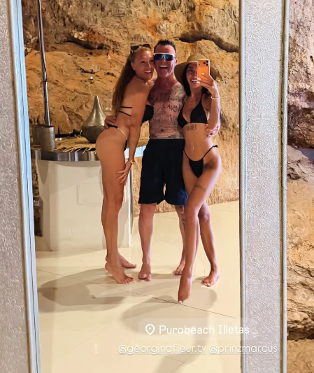 Drei Personen in Bademode posieren lachend für ein Spiegelselfie vor einer Felswand.