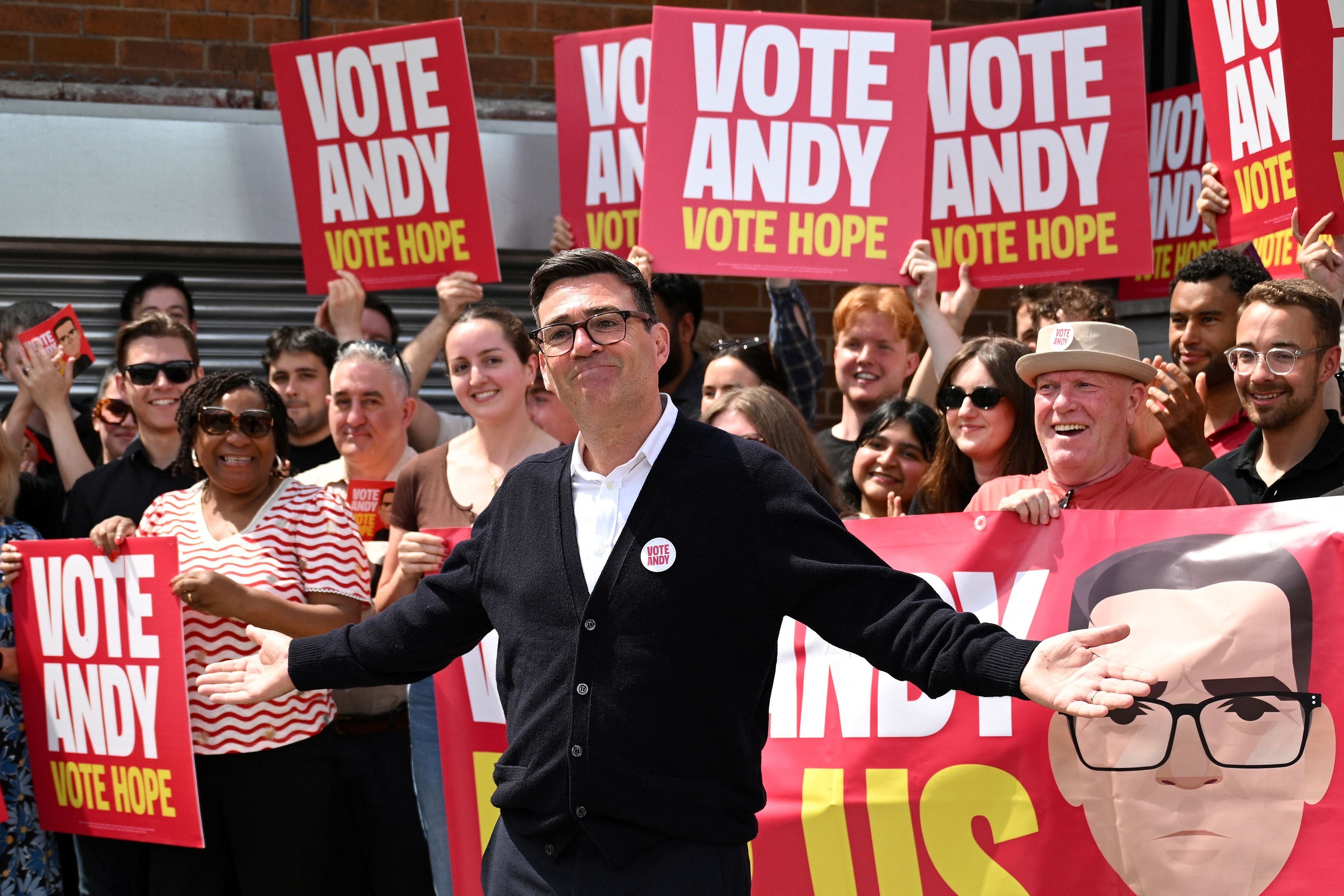Andy Burnham steht vor einer Gruppe von Unterstützern mit "VOTE ANDY"-Schildern.