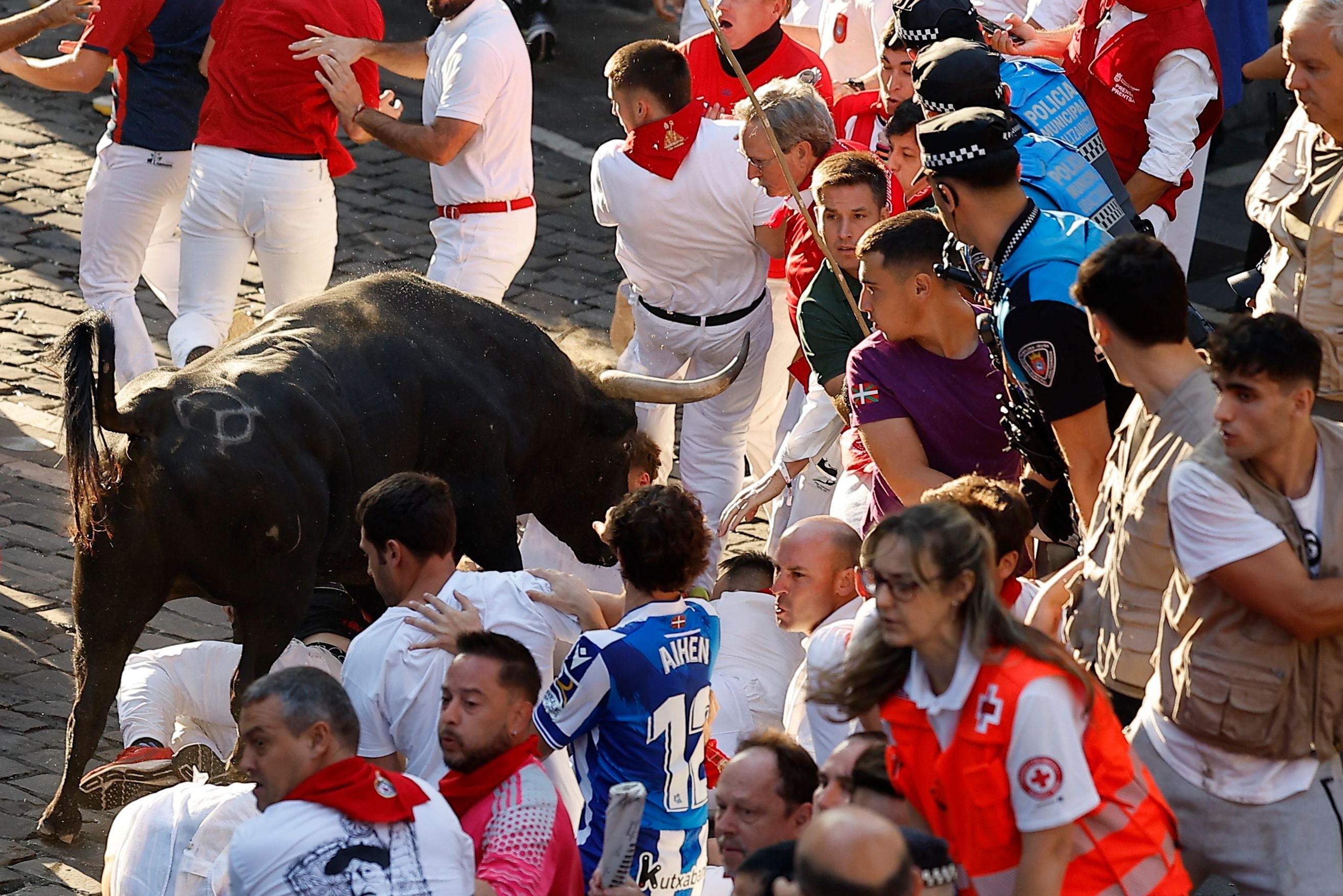 Ein Stier jagt mehrere Läufer während des San-Fermín-Festes in Pamplona durch eine Menschenmenge.