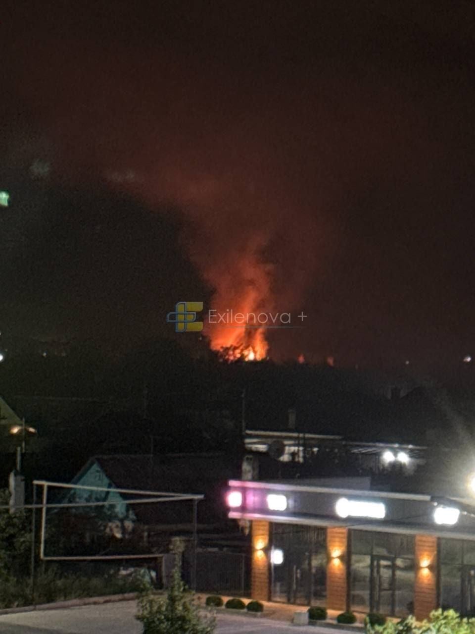 Großes Feuer mit starker Rauchentwicklung hinter Häusern bei Nacht im Ural.