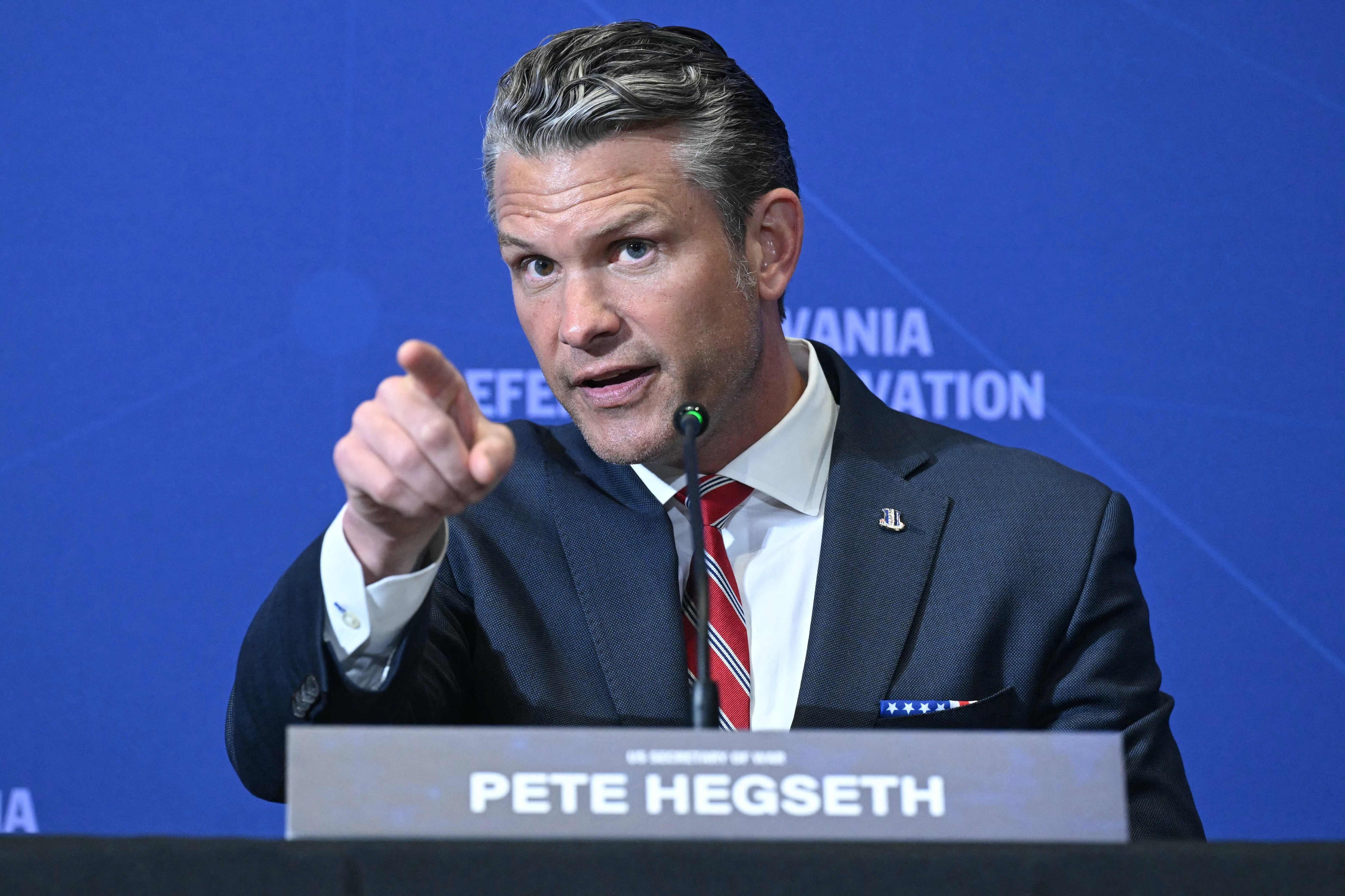 Ein Mann im Anzug spricht auf einer Konferenz und zeigt mit dem Finger nach vorne.