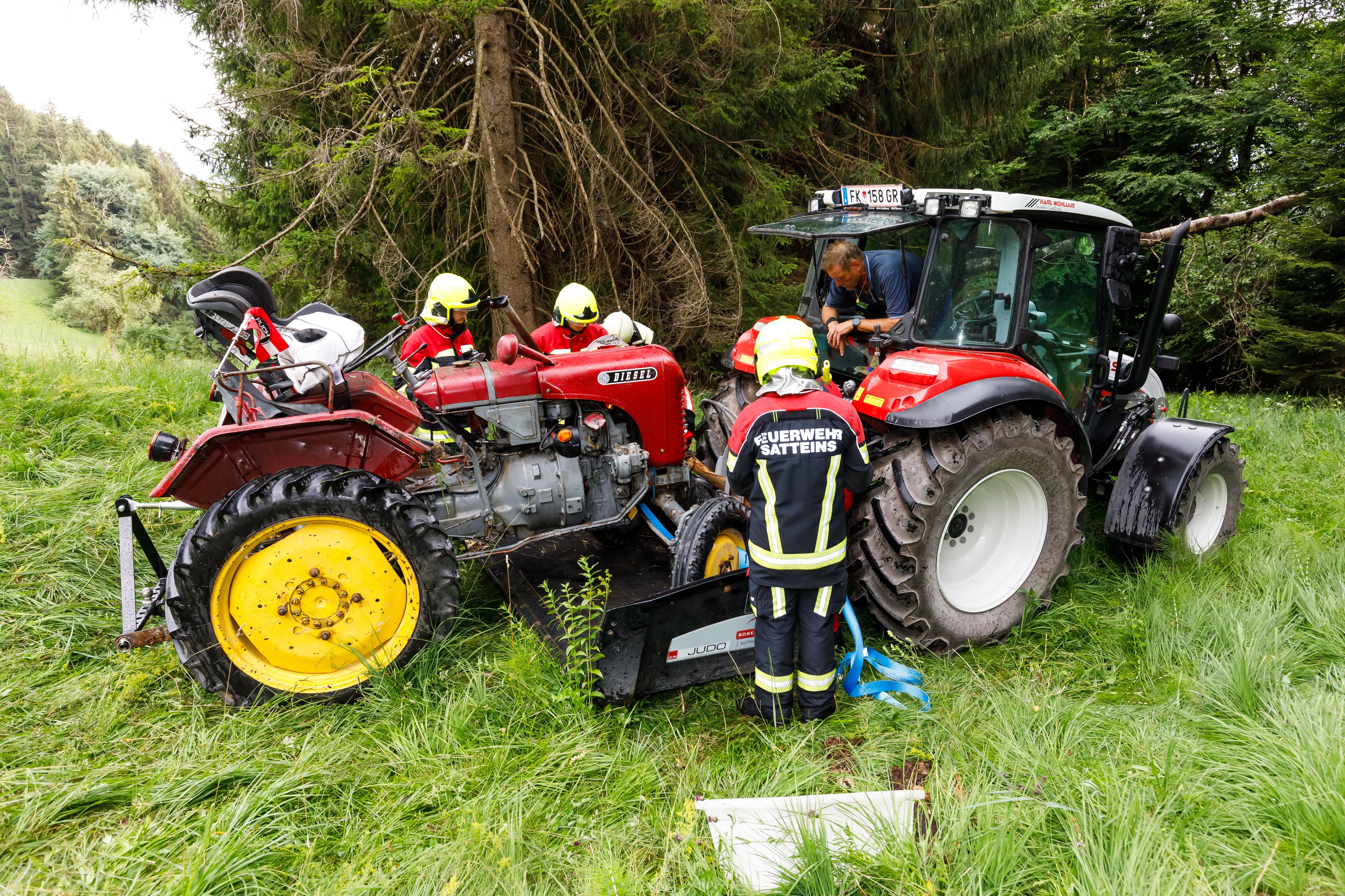 Feuerwehrleute sichern den verunfallten Traktor im Wald, ein weiterer Traktor steht daneben.