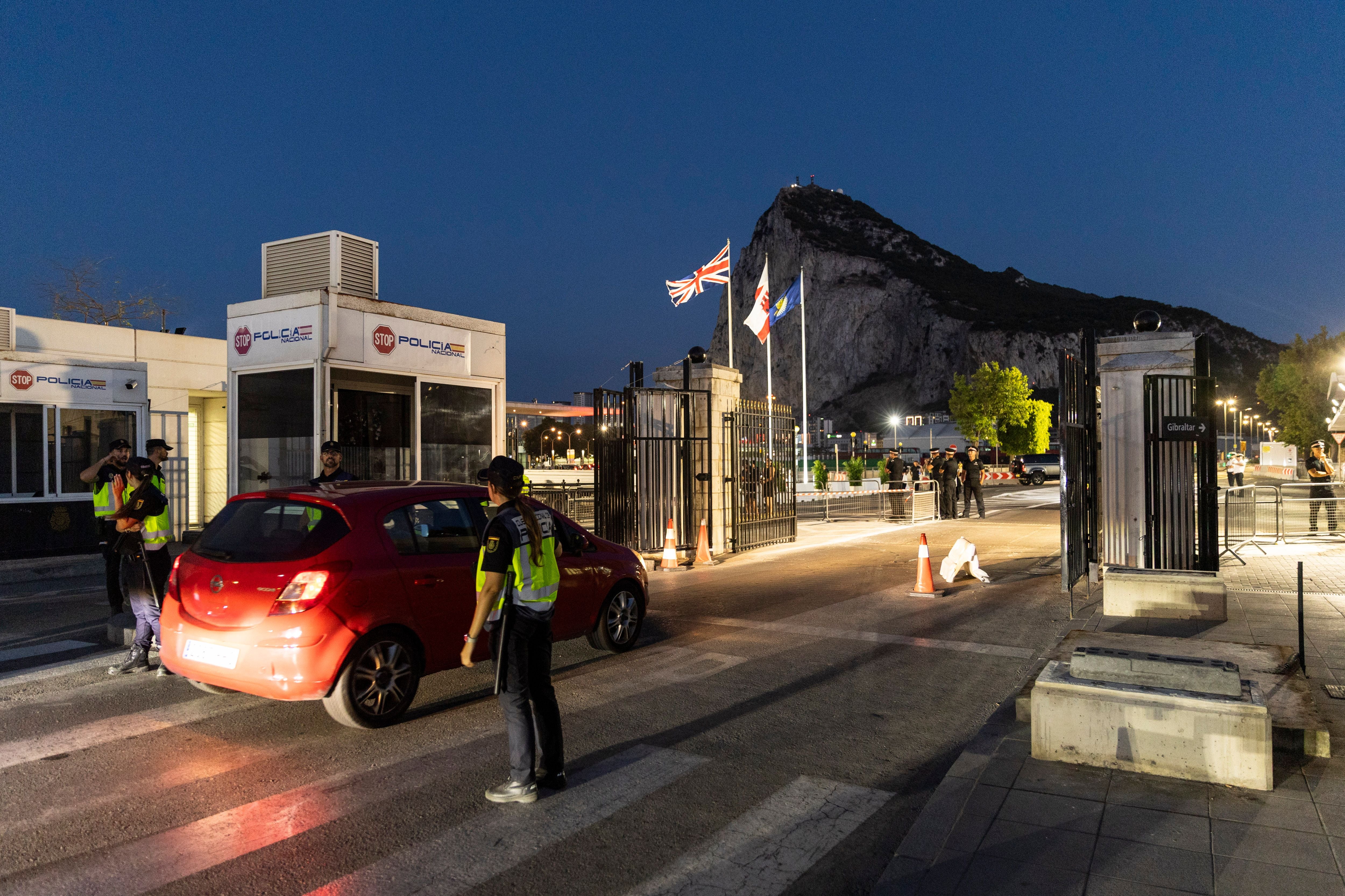 Spanische Polizei kontrolliert Auto am Grenzübergang zu Gibraltar bei Abenddämmerung.