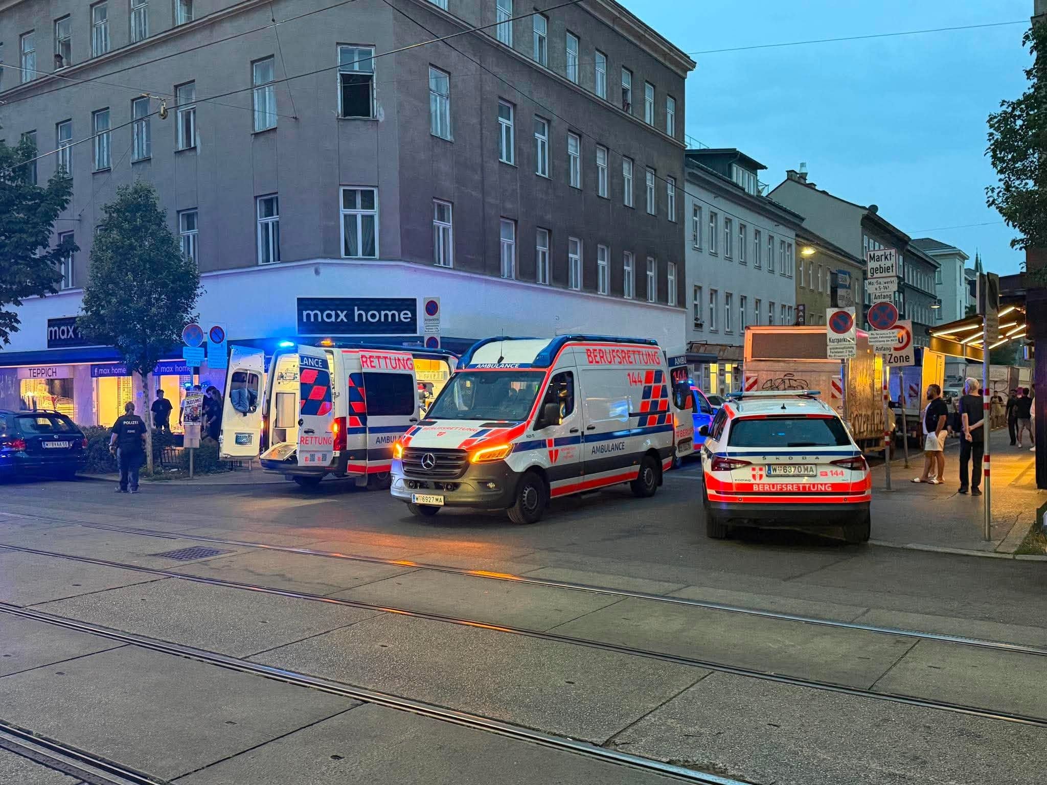 Mehrere Rettungs- und Polizeifahrzeuge stehen abends an einer Straßenecke in der Stadt.