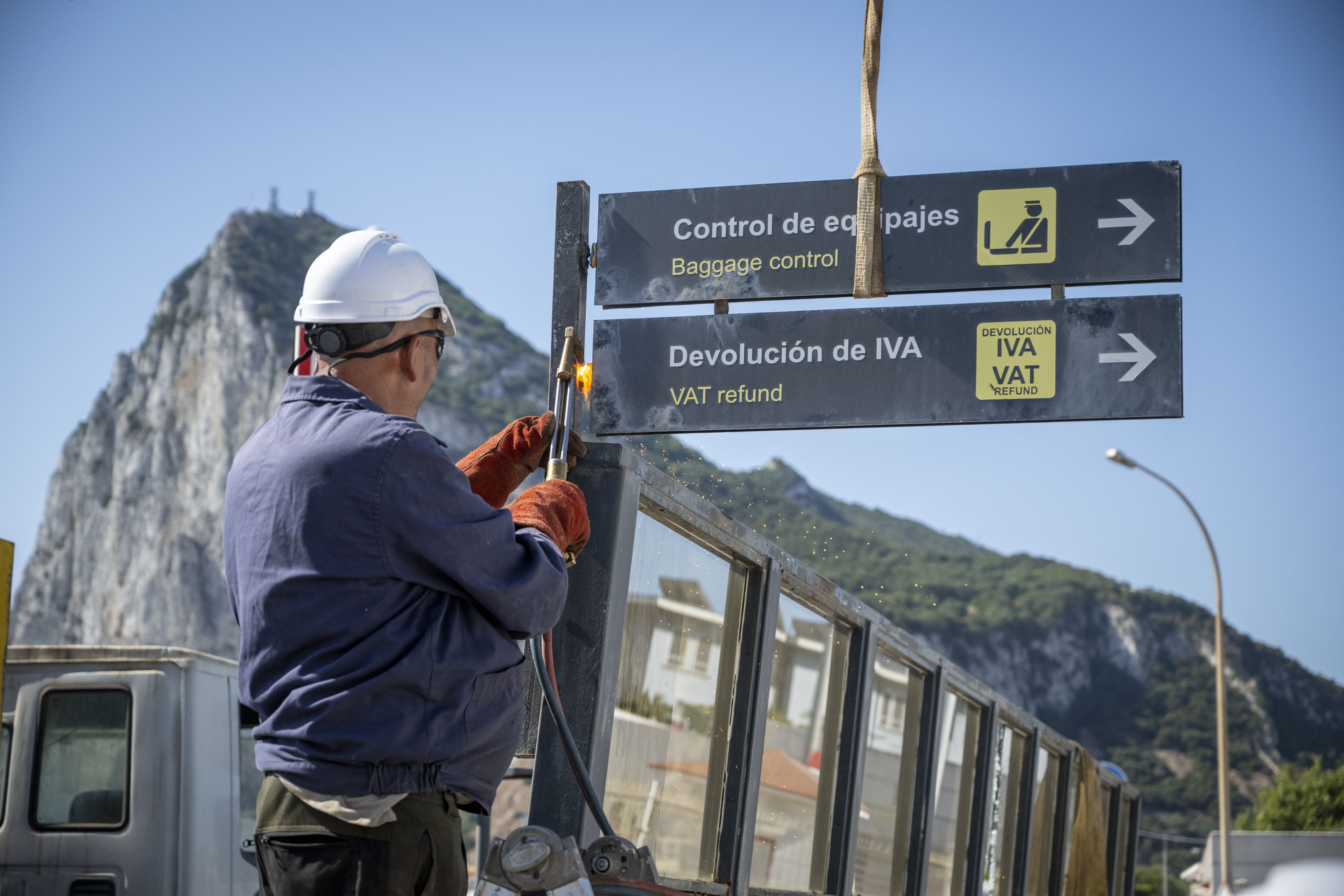 Bauarbeiter mit Helm arbeitet an einem Grenzschild zwischen Spanien und Gibraltar.