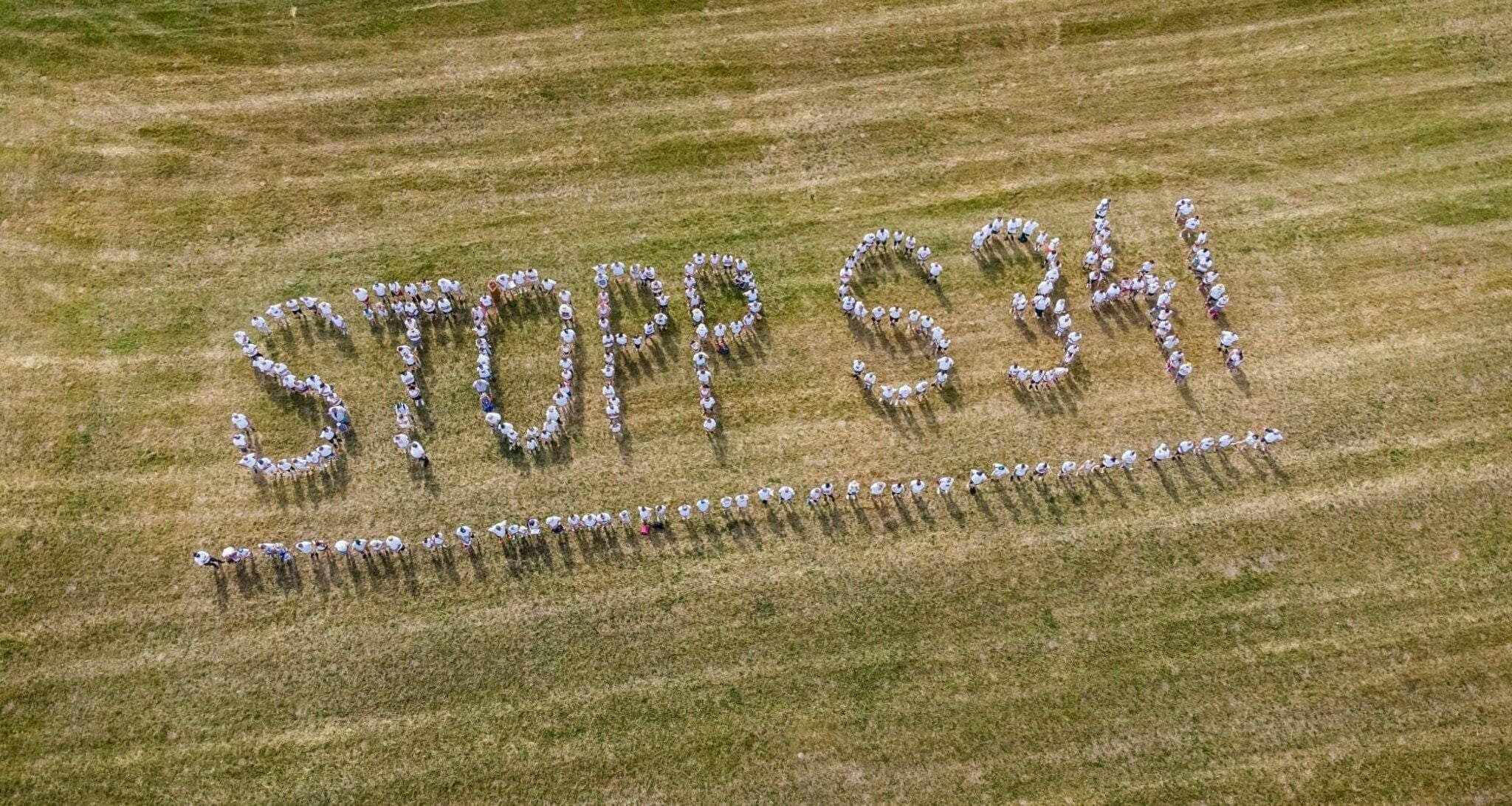 Menschen bilden auf einer Wiese den Schriftzug „STOPP S34!“ aus der Vogelperspektive.