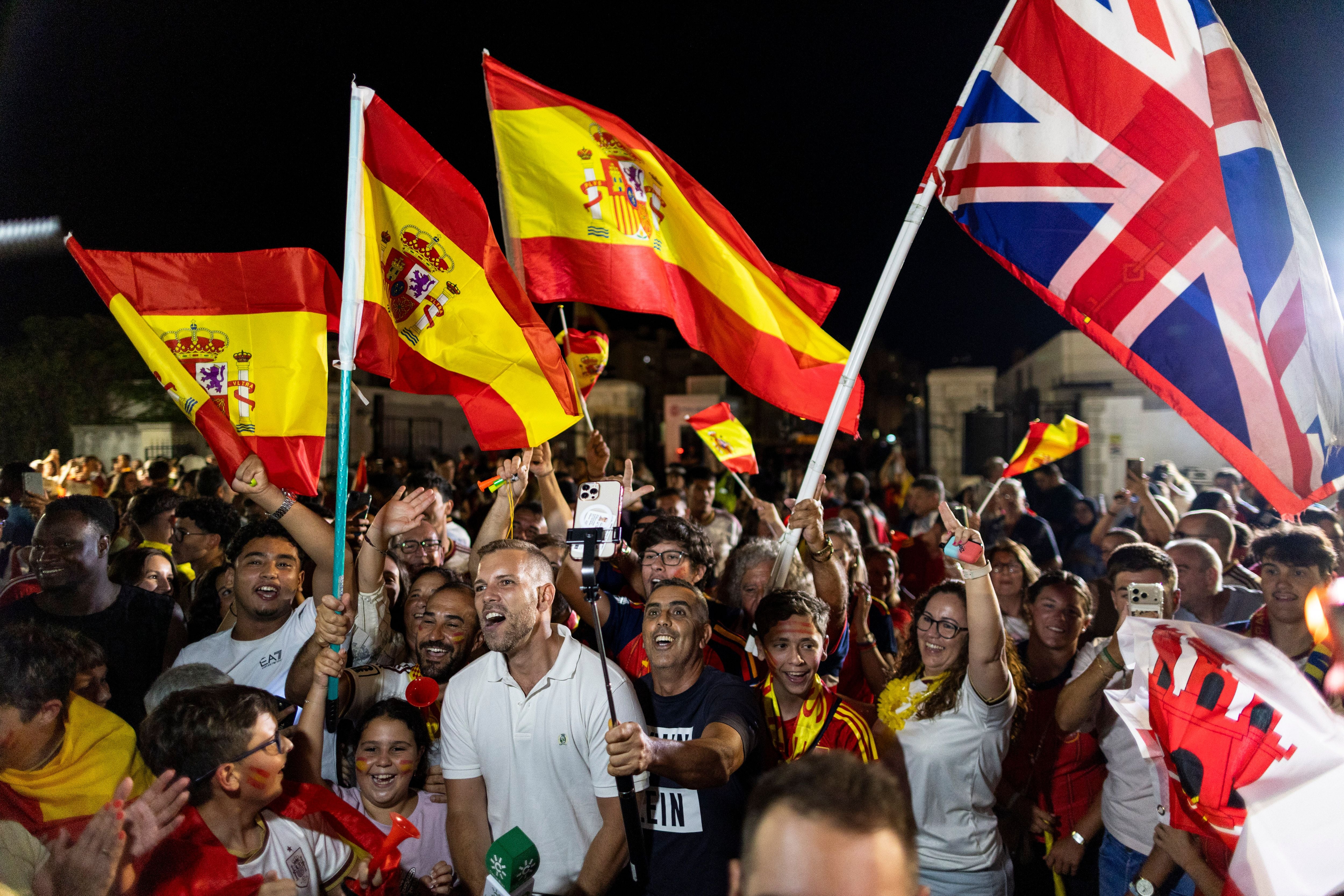 Menschen jubeln nachts mit spanischen und britischen Flaggen bei Feierlichkeiten an der Grenze Gibraltars.