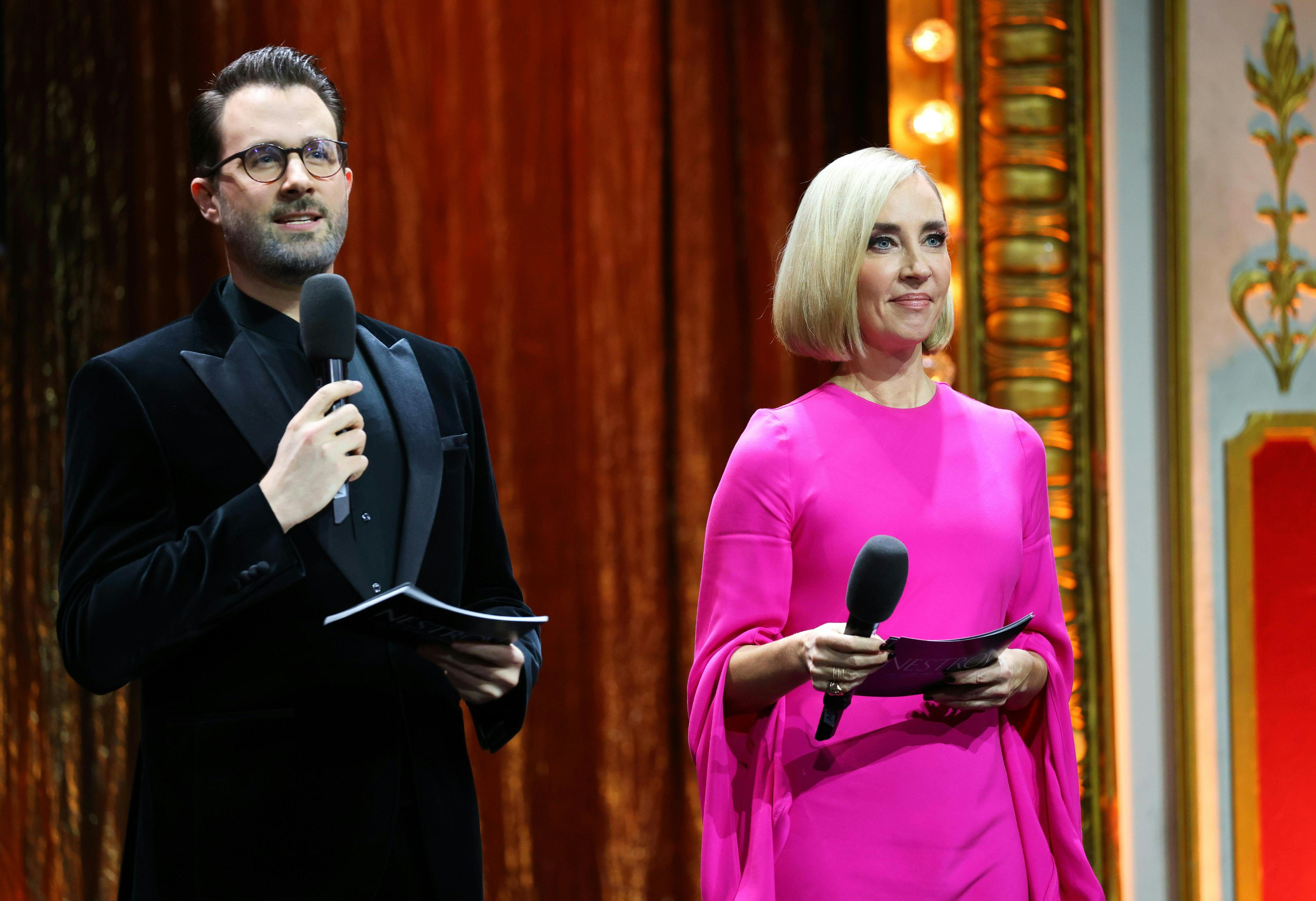 Zwei Moderatoren mit Mikrofonen stehen auf einer Bühne beim Nestroy-Theaterpreis in Wien.