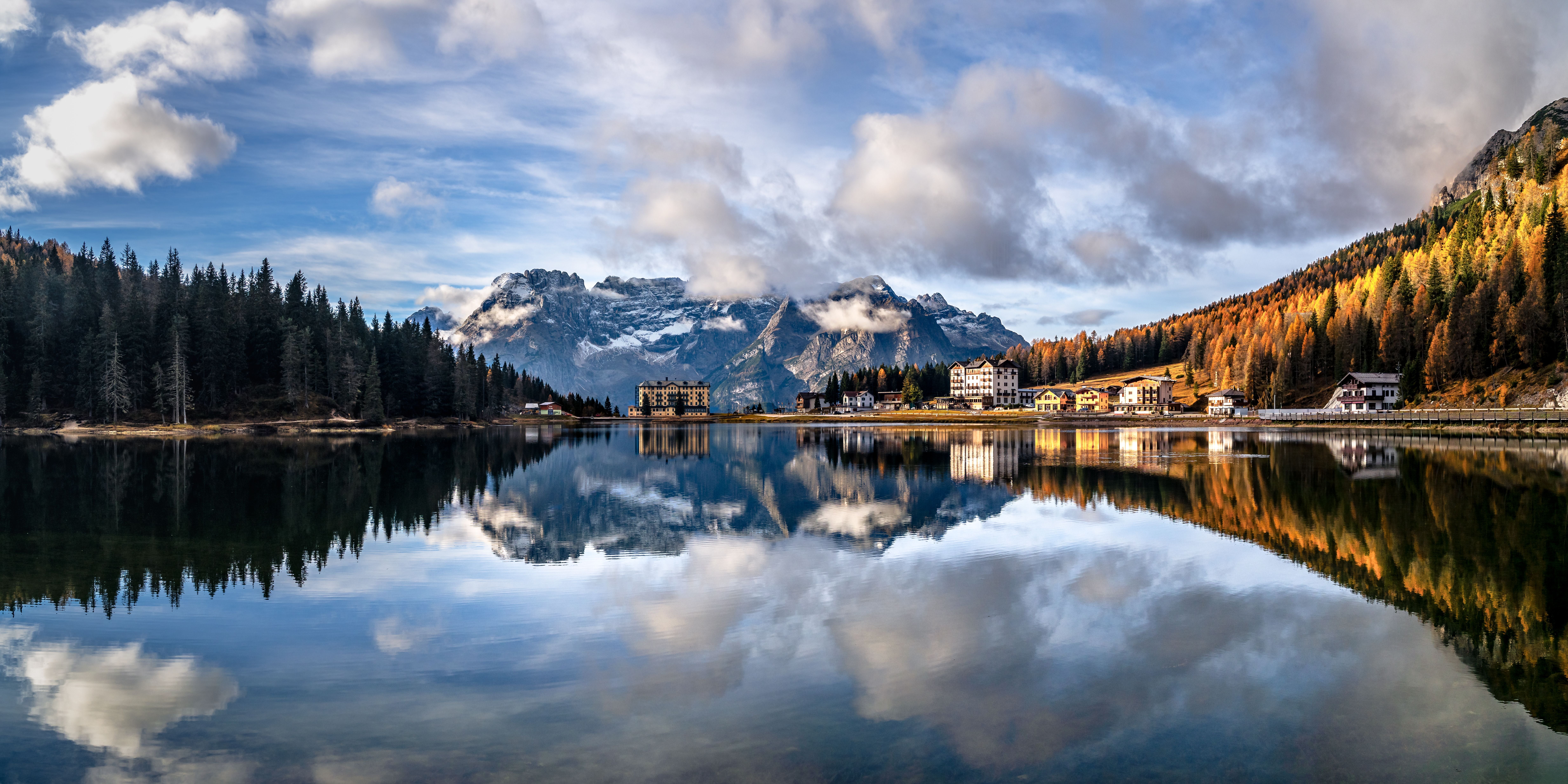 Sorapis-Gebirge spiegelt sich nach Sonnenaufgang im Misurinasee, umgeben von herbstlichen Wäldern.