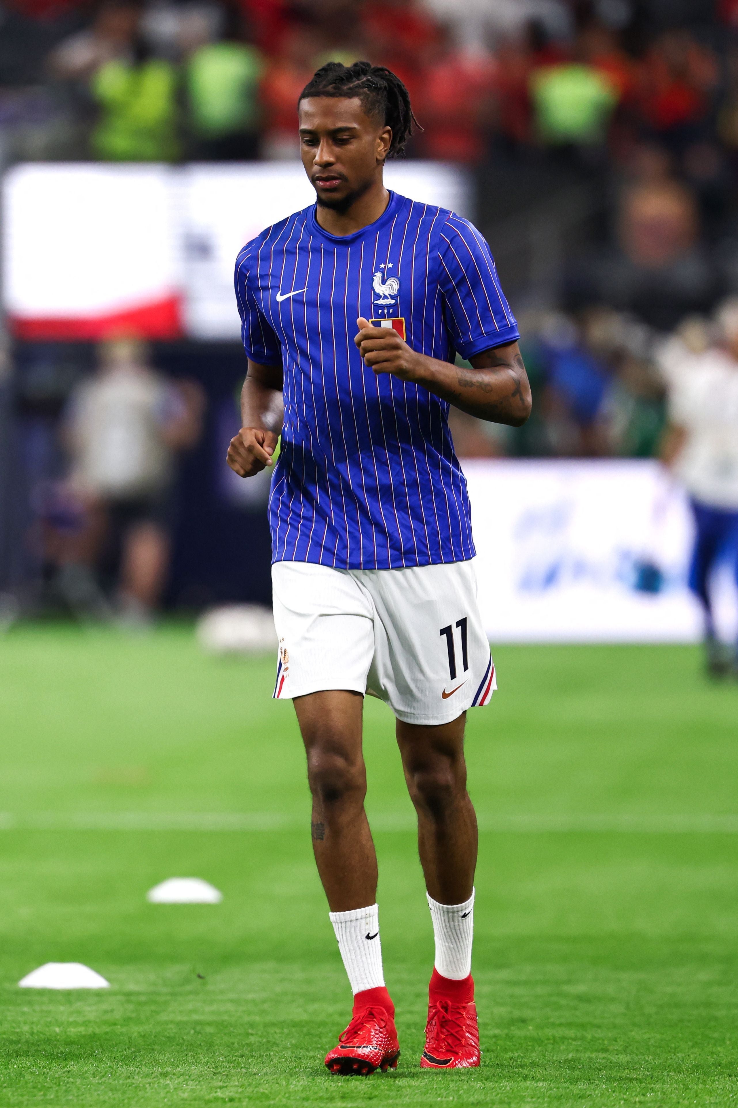 Ein französischer Fußballspieler wärmt sich im blauen Trikot mit der Nummer 11 auf dem Spielfeld auf.