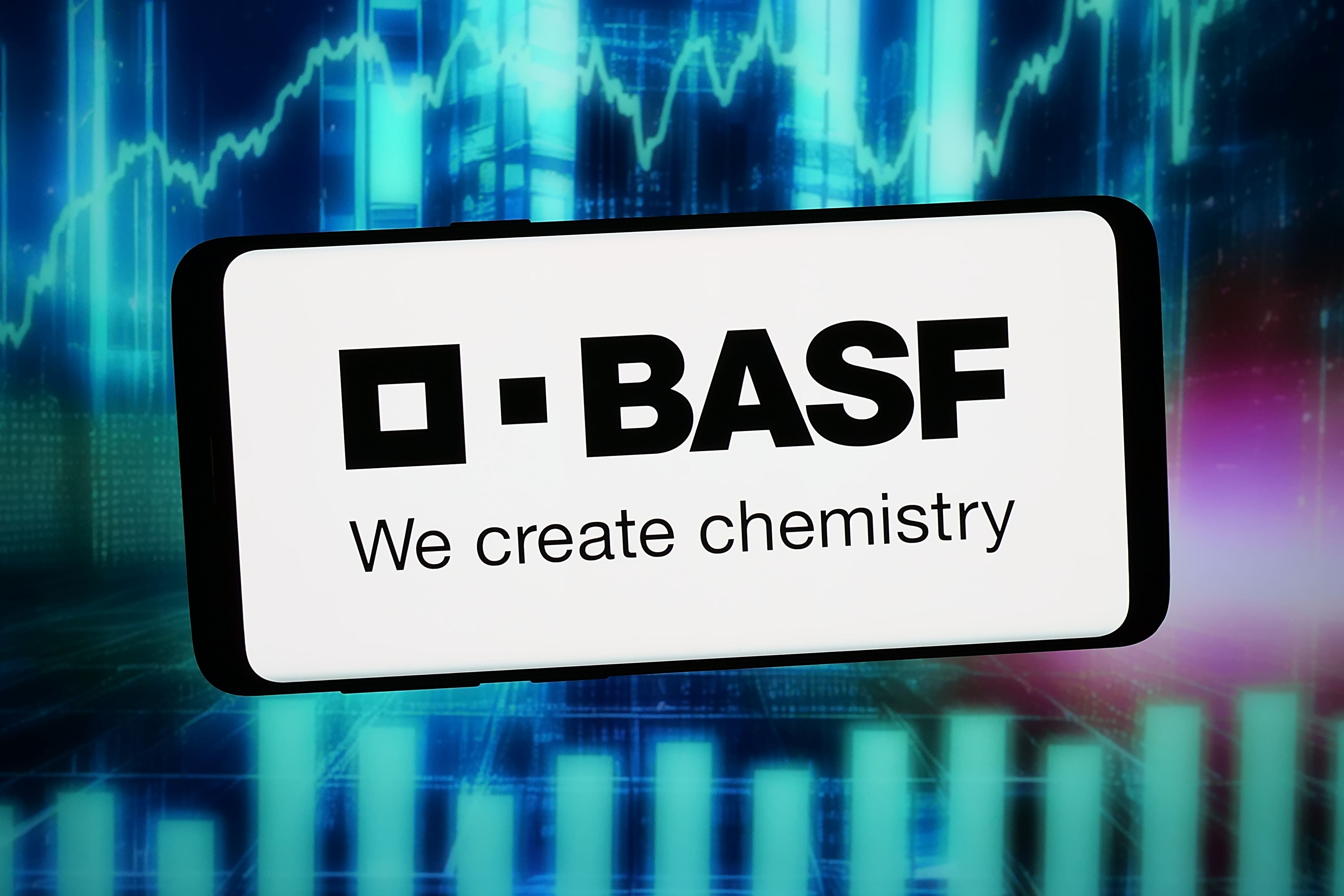 BASF-Logo und Slogan auf Smartphone vor abstraktem, blauem Hintergrund mit Kurvendiagrammen.