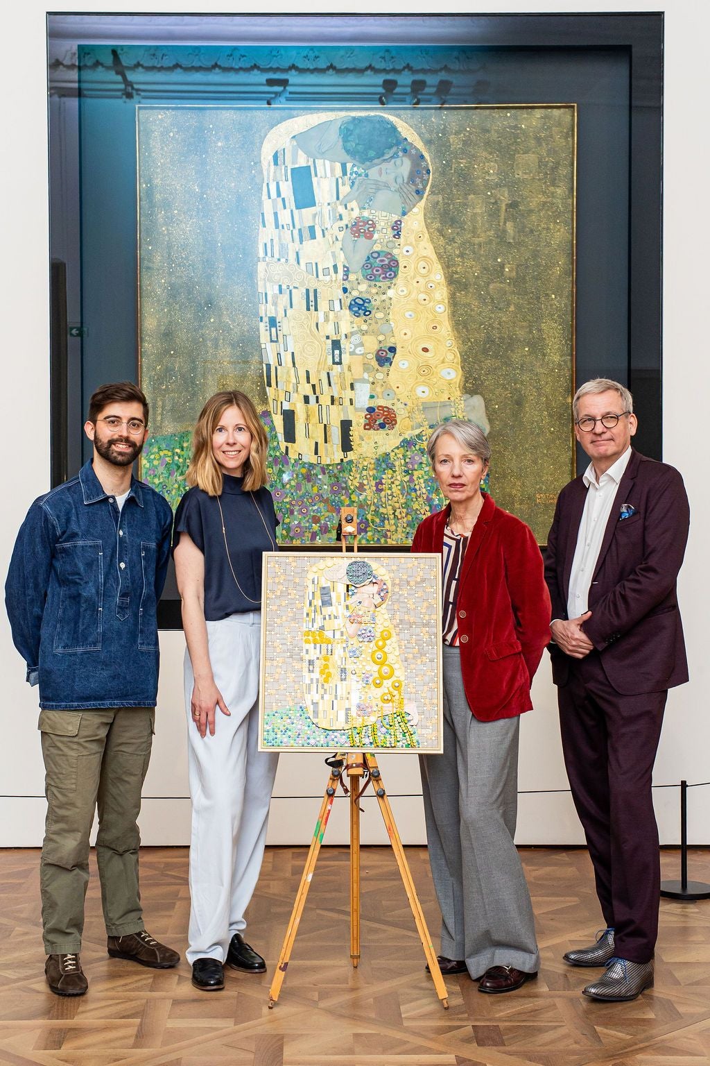Vier Personen stehen vor einem Gemälde von Klimts "Der Kuss" und einem LEGO-Nachbau auf einer Staffelei.