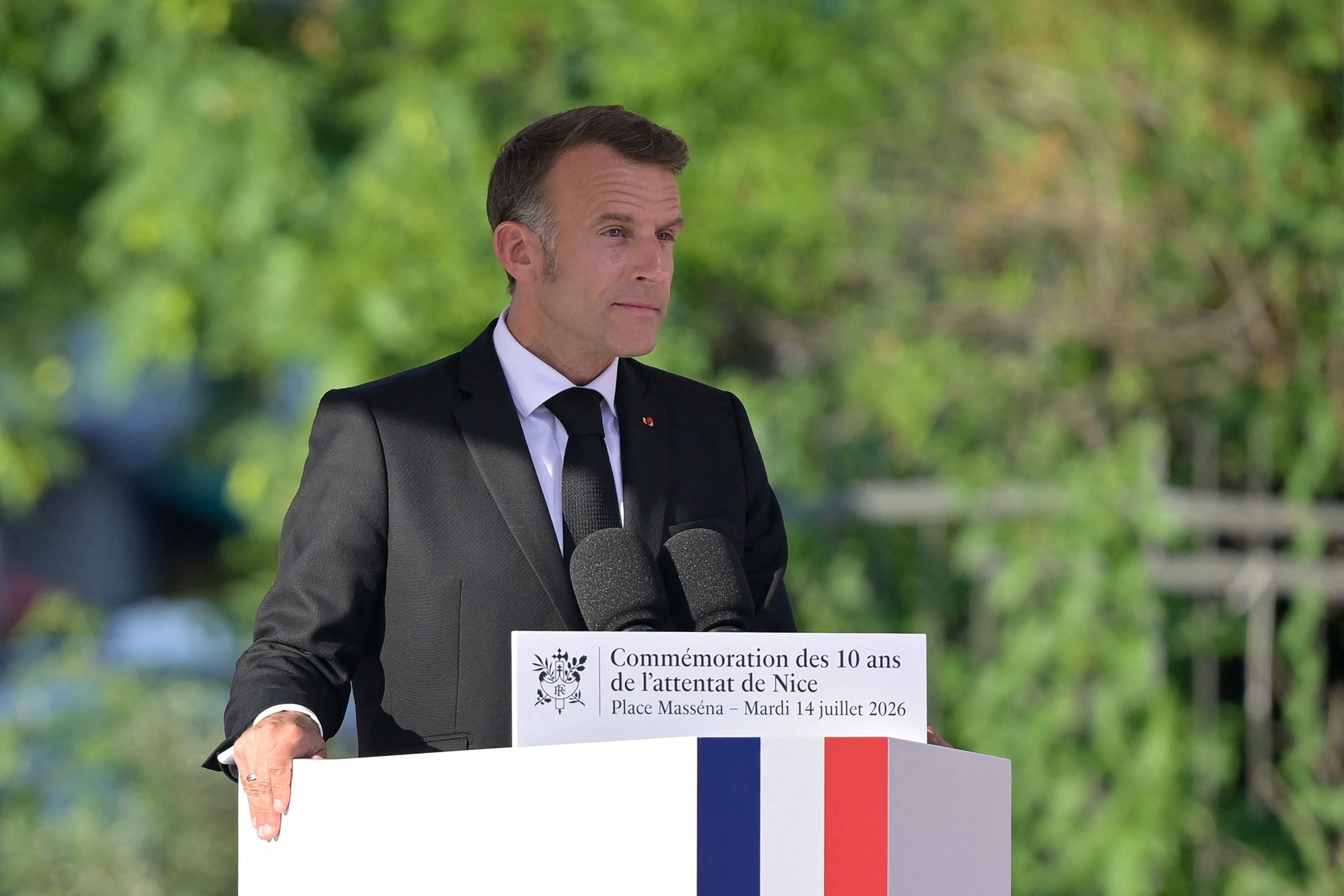 Ein Mann im Anzug hält eine Rede bei einer Gedenkzeremonie in Frankreich im Freien.