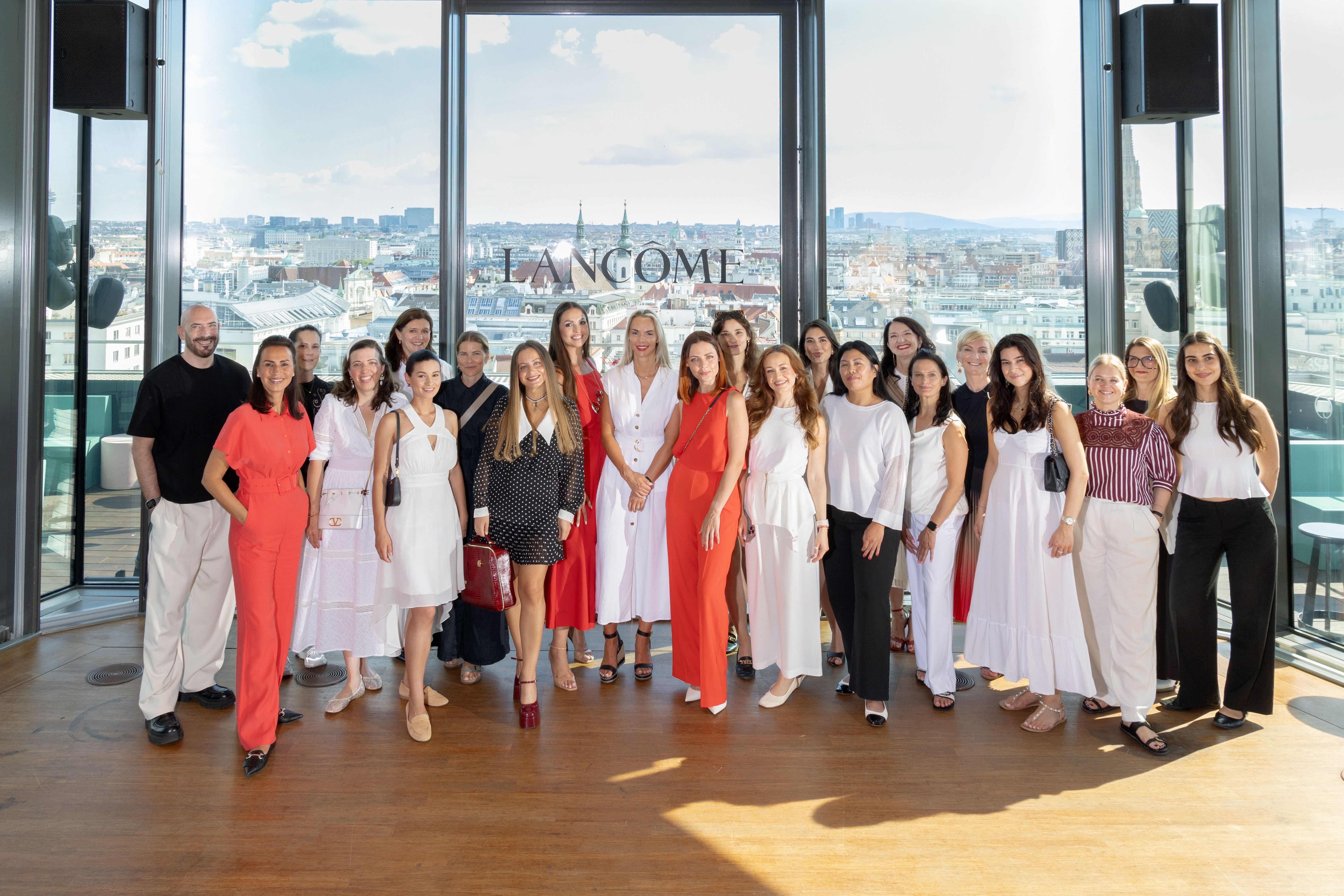 Gruppenfoto mehrerer Frauen und eines Mannes bei einer Beauty-Masterclass mit Stadtblick im Hintergrund.