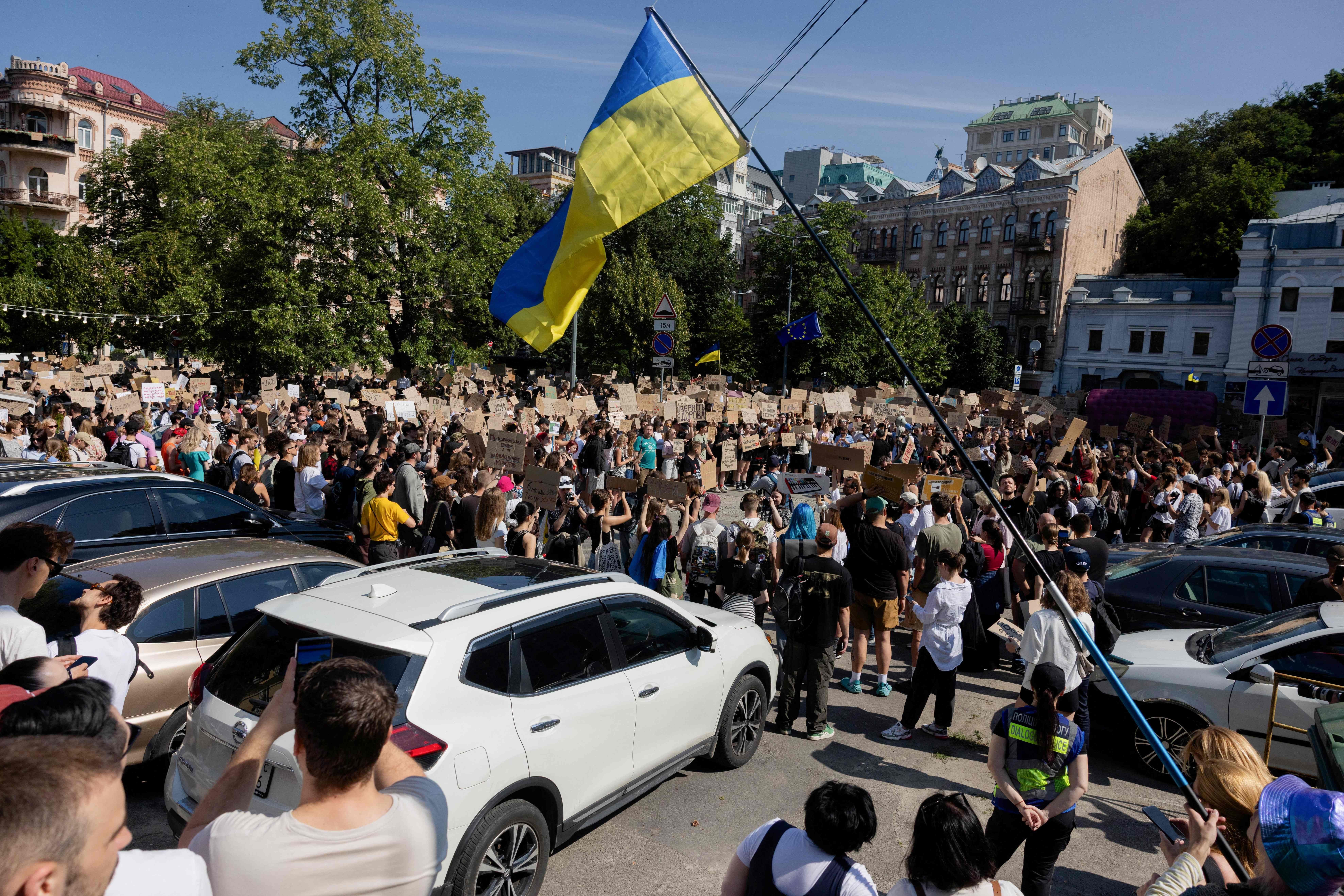 Große Menschenmenge demonstriert in Kiew mit ukrainischer Flagge und Protestschildern auf der Straße.