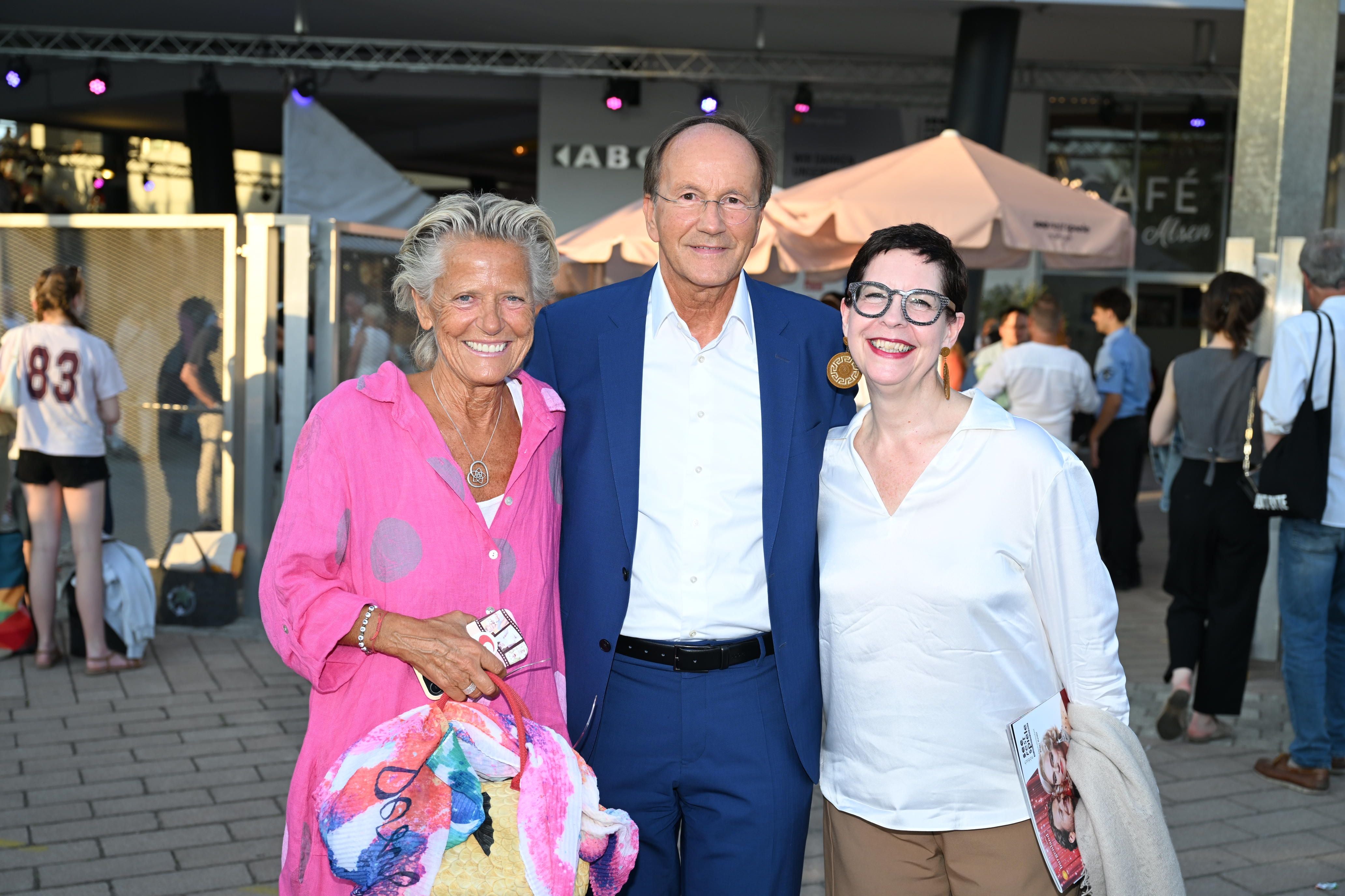 Drei lächelnde Personen posieren beim Seefestspiele Mörbisch im Freien für ein Foto.