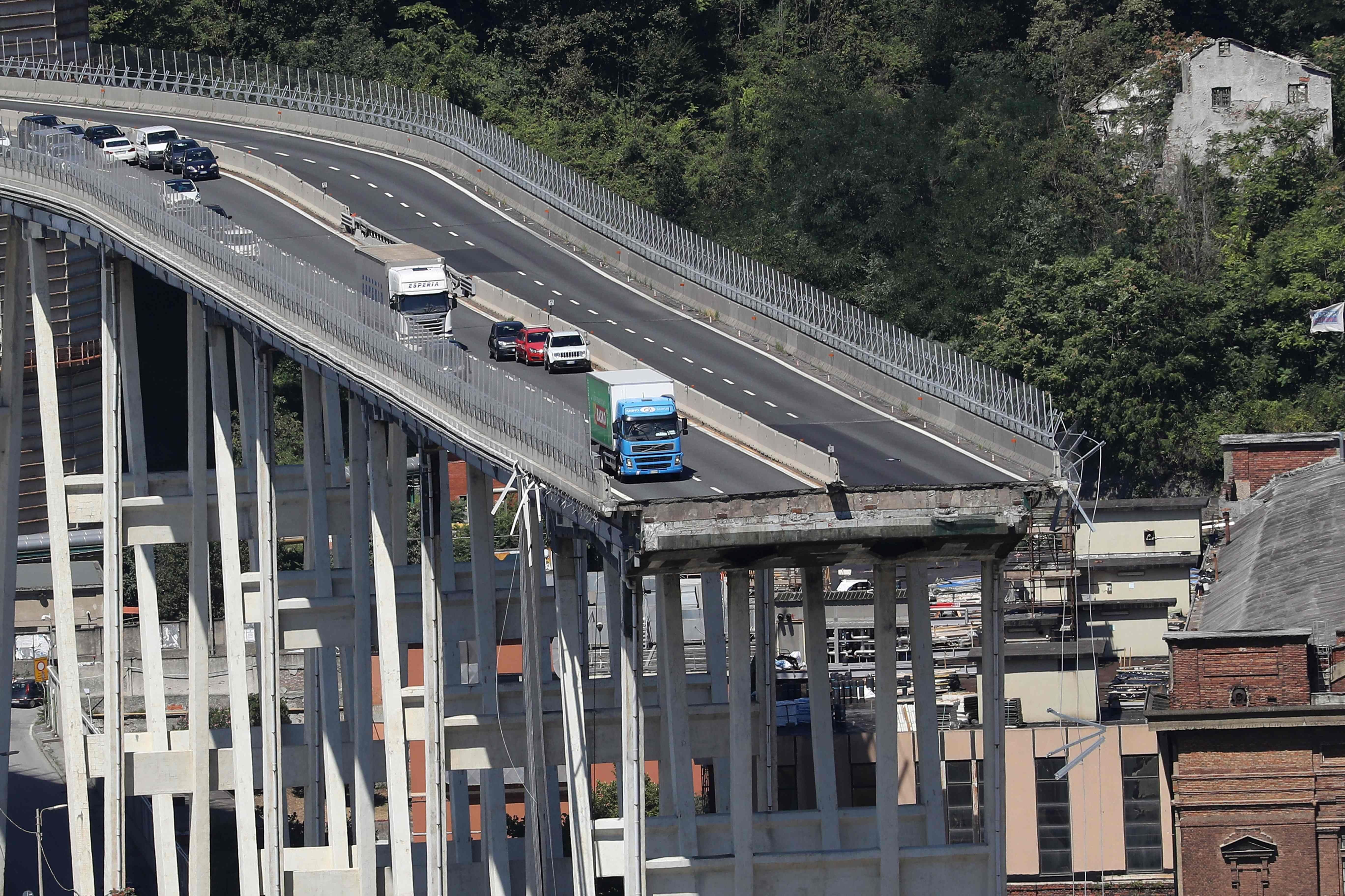 Lastwagen und Autos stehen auf einer abrupt abgebrochenen Brücke in Genua, Italien.