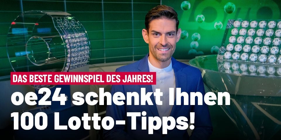 Ein Mann im Anzug hält ein Lotto-Maskottchen in einem Fernsehstudio für die Lottoziehung.