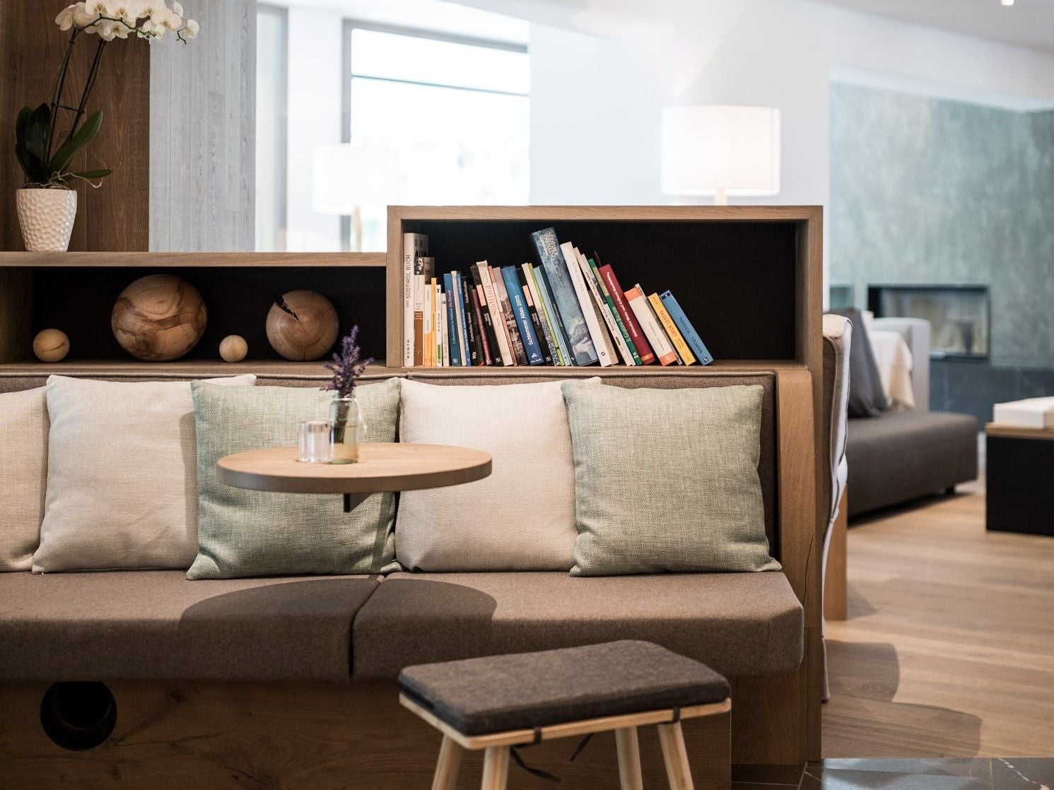 Moderne Hotellounge mit Sofa, Kissen, Bücherregal und kleiner Tischdekoration.