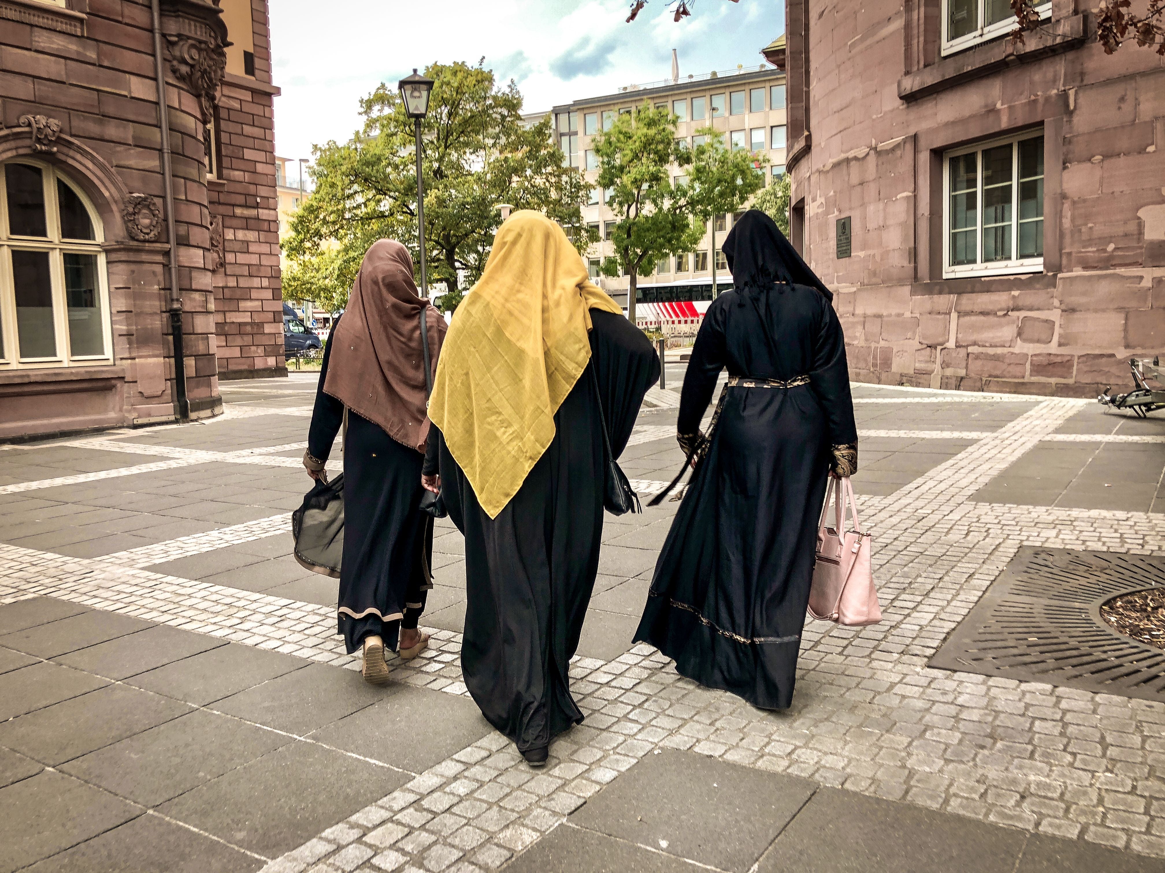 Drei Frauen in traditionellen Gewändern gehen durch eine Altstadtstraße in Berlin.