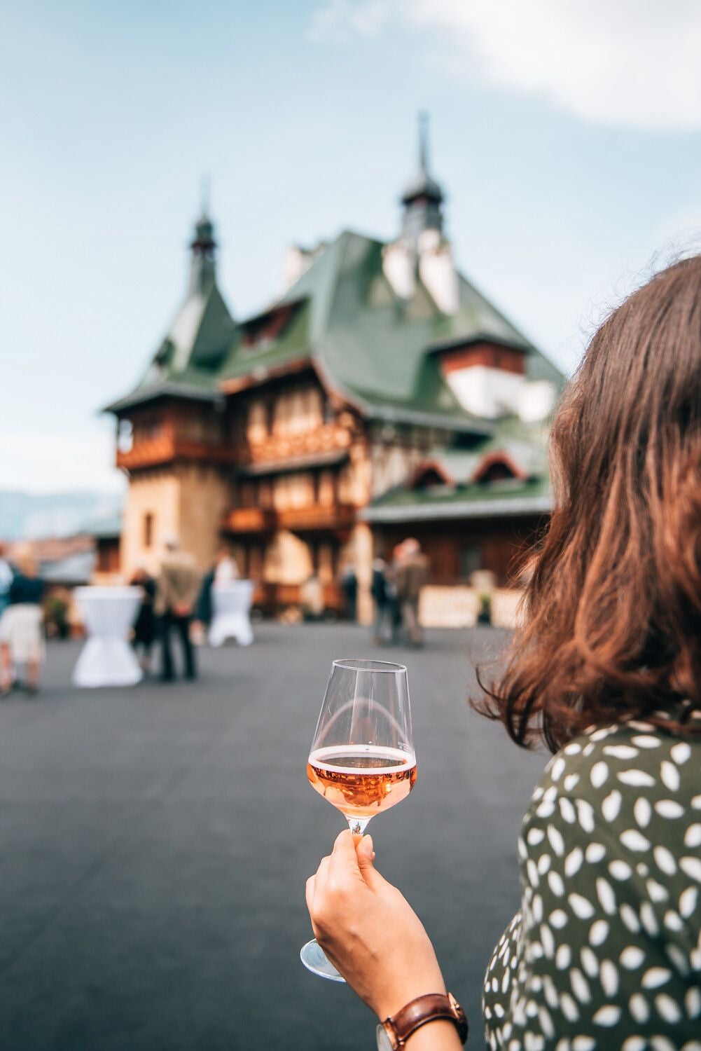 Frau hält ein Glas Roséwein vor einem historischen Gebäude in Semmering, Wiener Alpen.