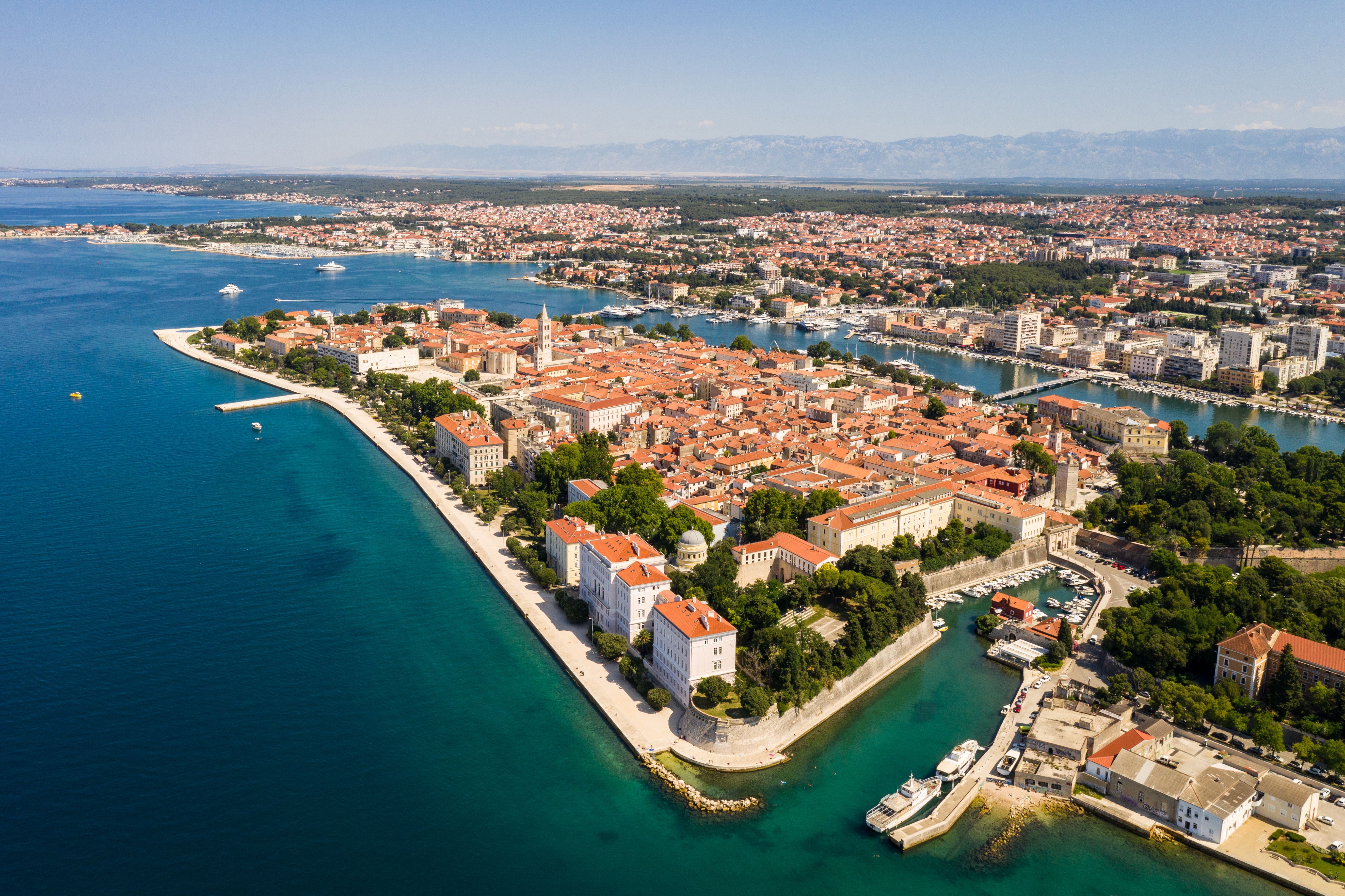 Luftaufnahme der Altstadt von Zadar an der Adriaküste in Kroatien mit roten Dächern und blauem Meer.