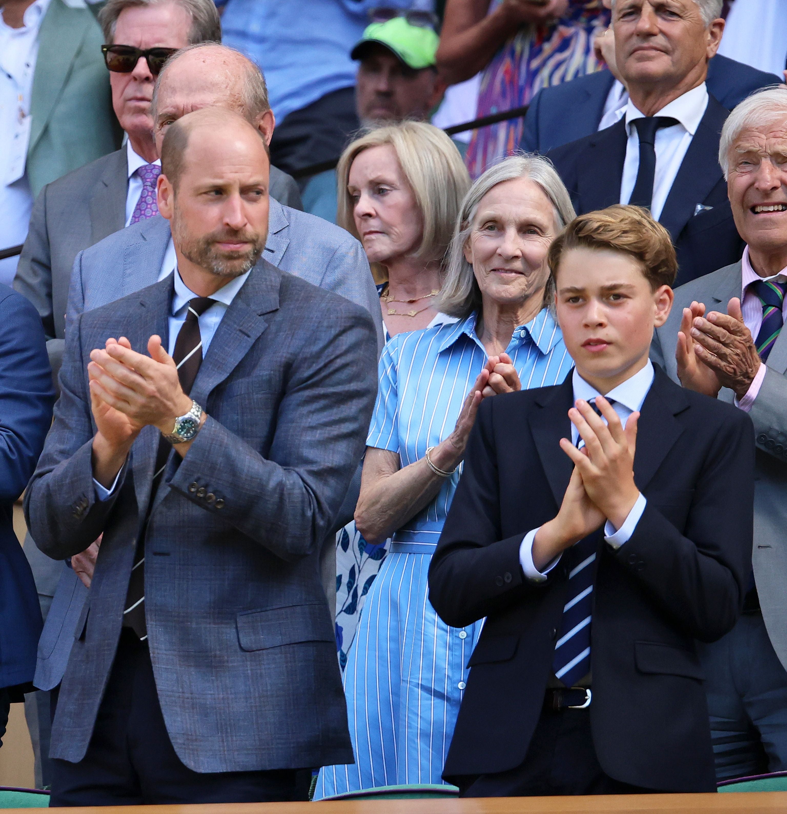 Ein Mann im Anzug und ein Junge im Sakko klatschen in einer Menschenmenge bei einem Tennis-Event.