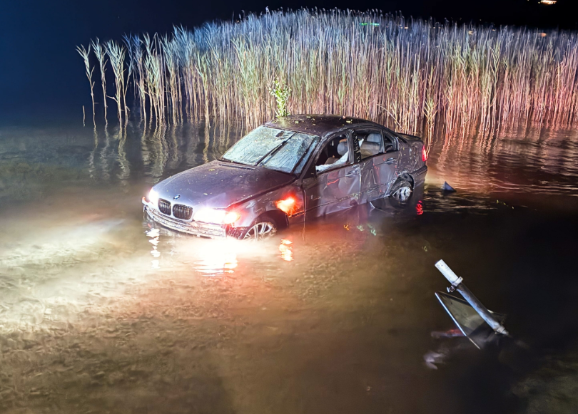 Beschädigtes Auto steht nach Unfall teils unter Wasser im Wörthersee bei Schilfgras.