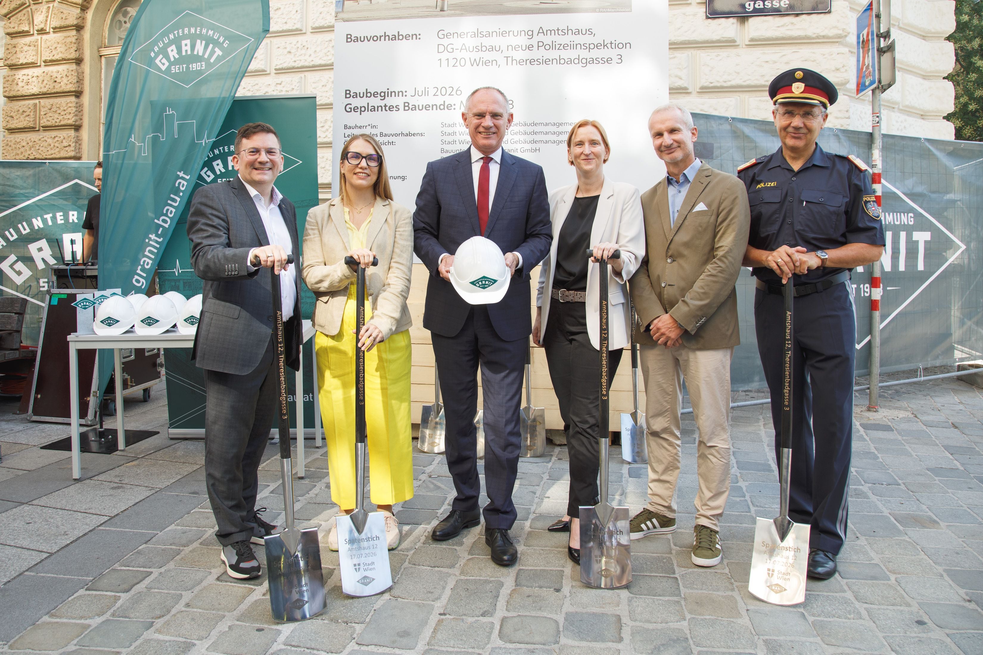 Sechs Personen stehen mit Spaten bei einem Spatenstich für eine neue Polizeiinspektion in Wien.