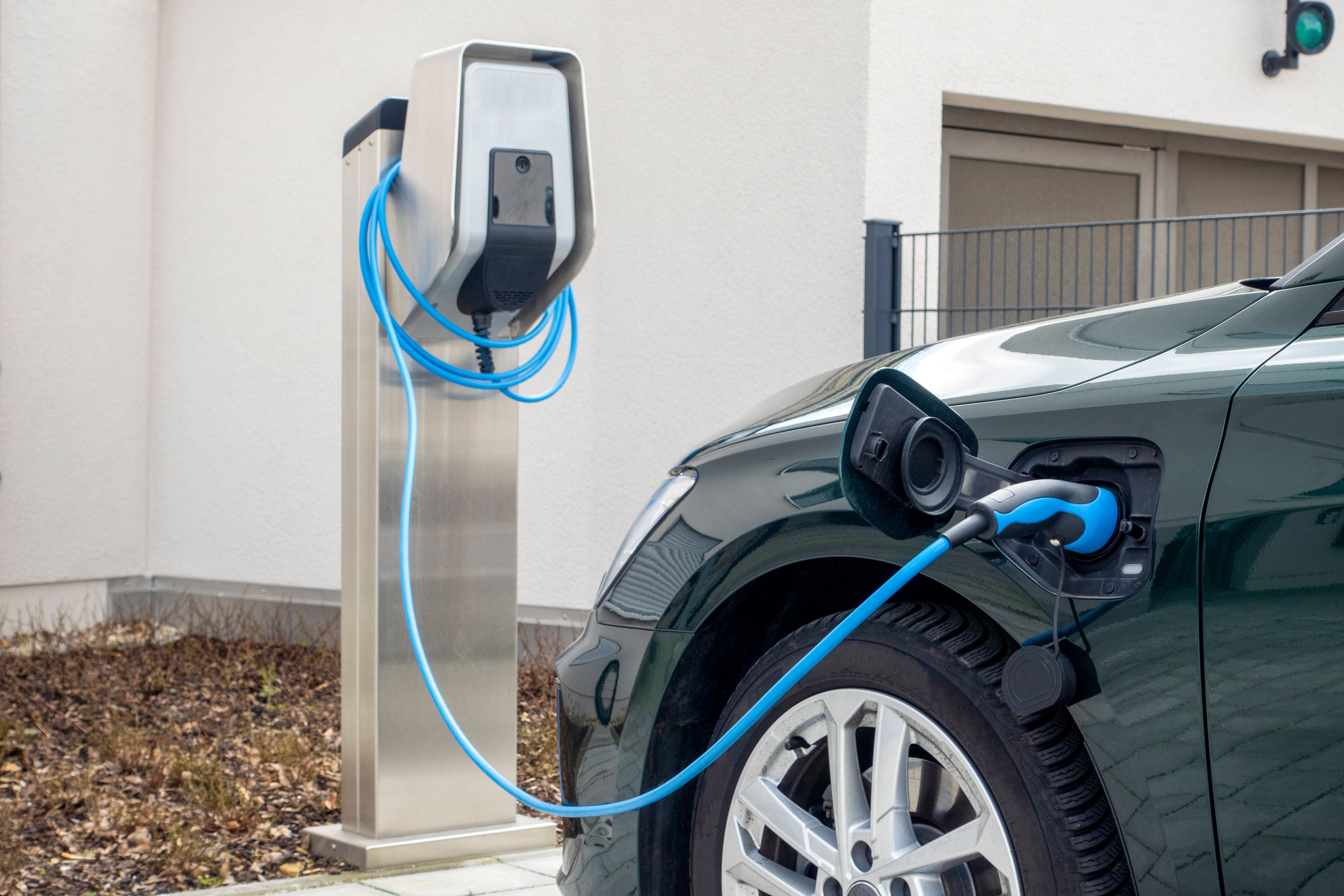 Ein Elektroauto wird an einer Ladestation mit einem blauen Kabel aufgeladen.