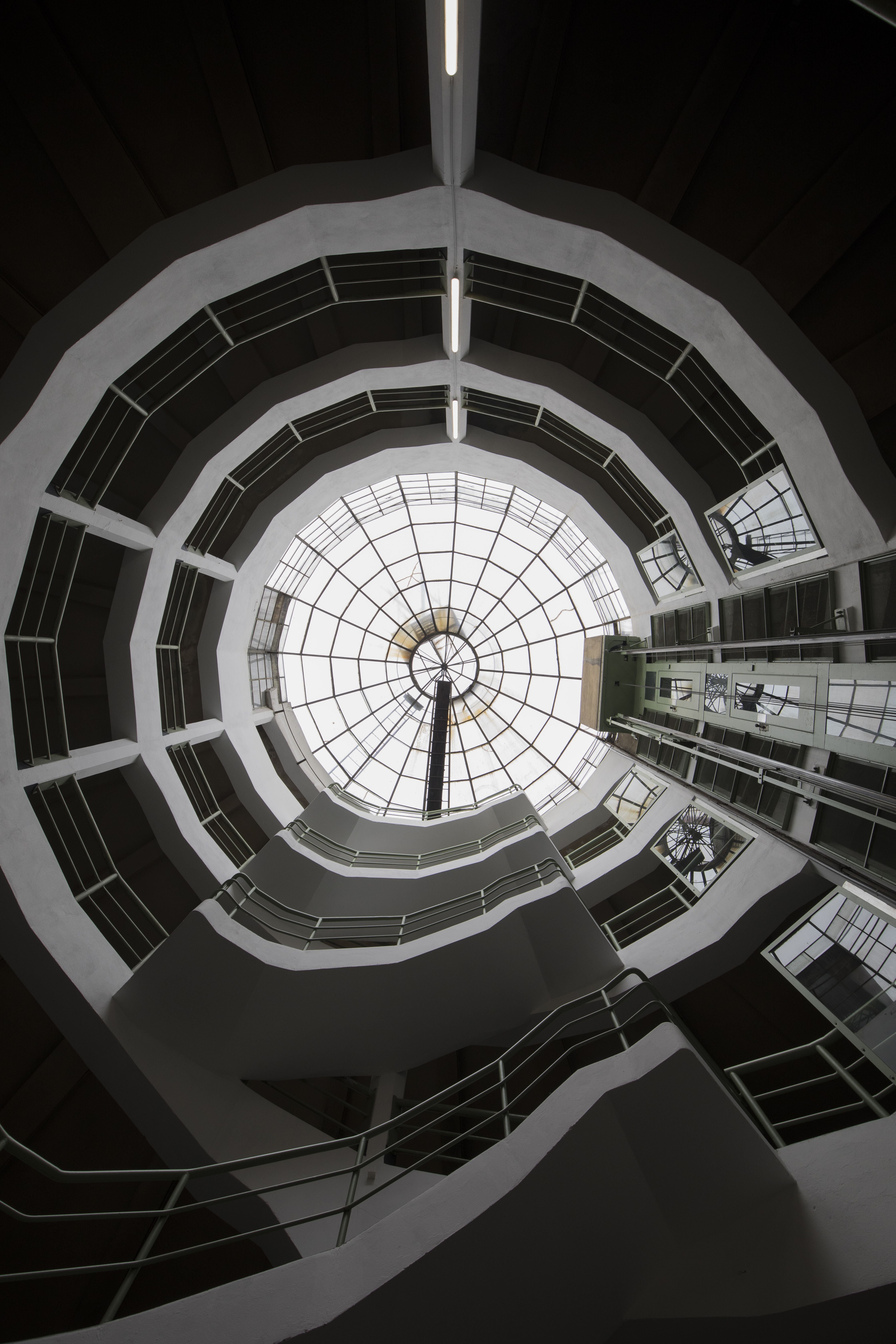 Blick von unten auf ein mehrstöckiges Treppenhaus mit rundem Glasdach.