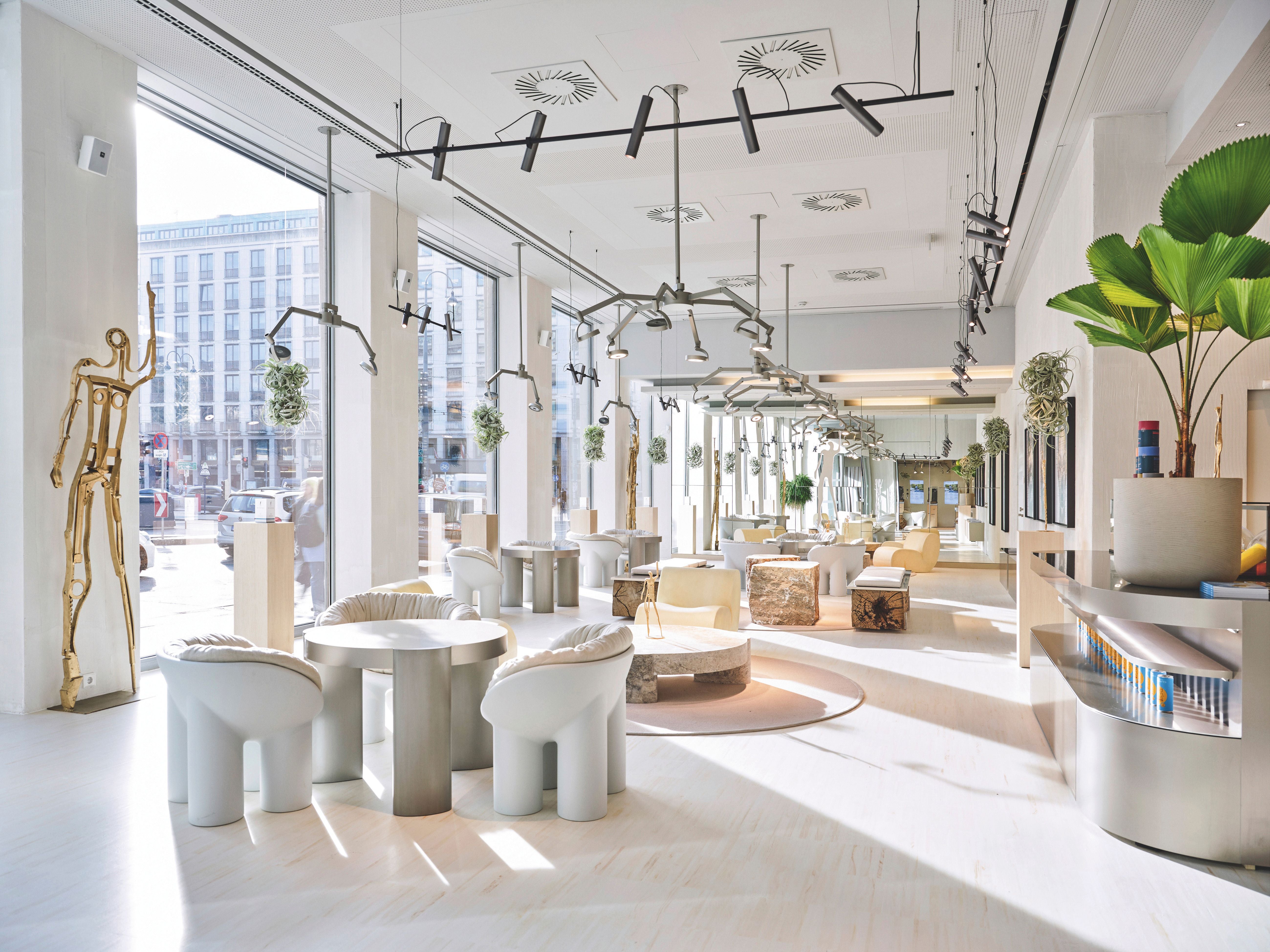 Modernes, helles Café mit Designermöbeln, großen Fenstern und Pflanzen im Innenraum.