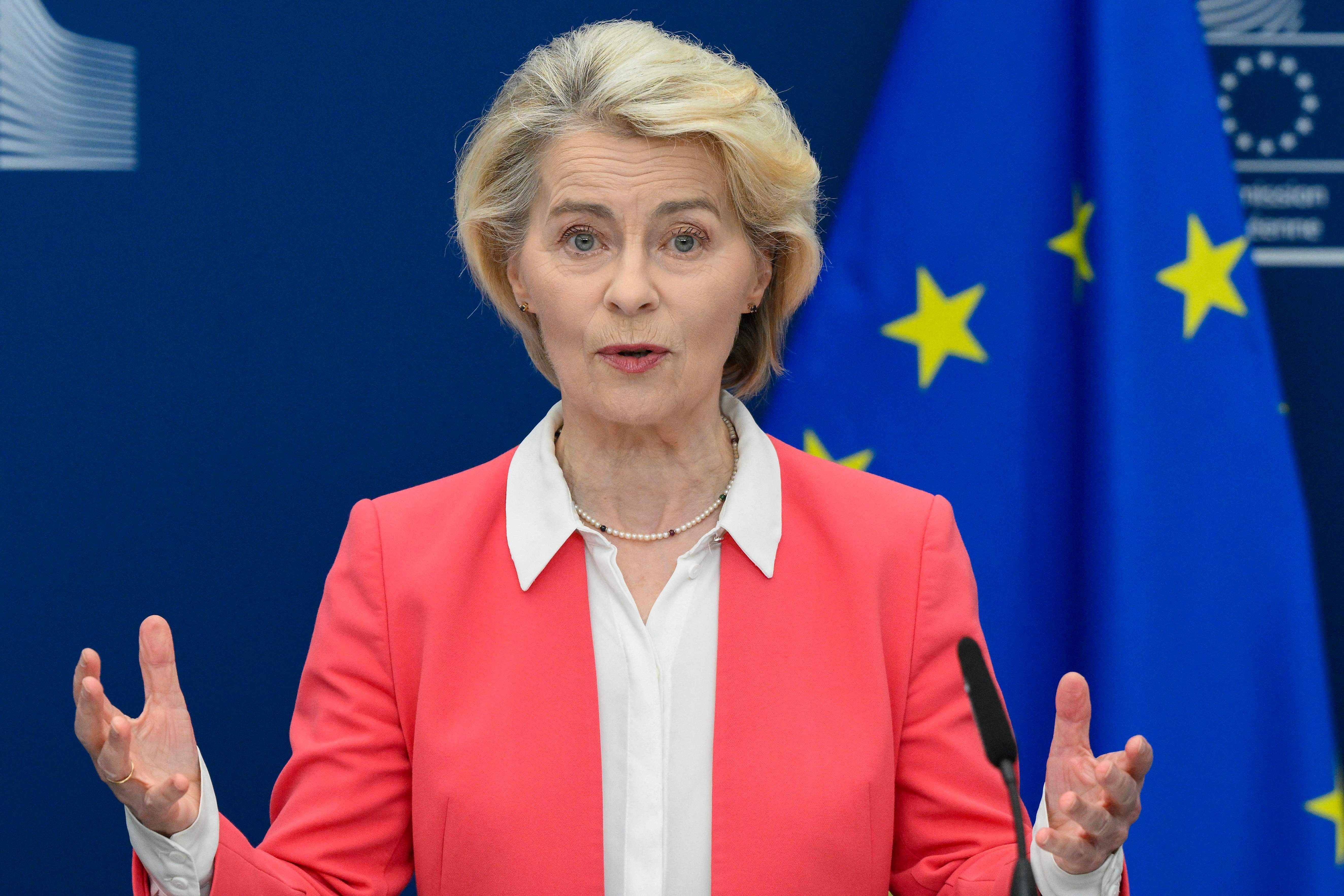 Frau spricht bei einer Pressekonferenz vor EU-Flaggen und gestikuliert mit den Händen.