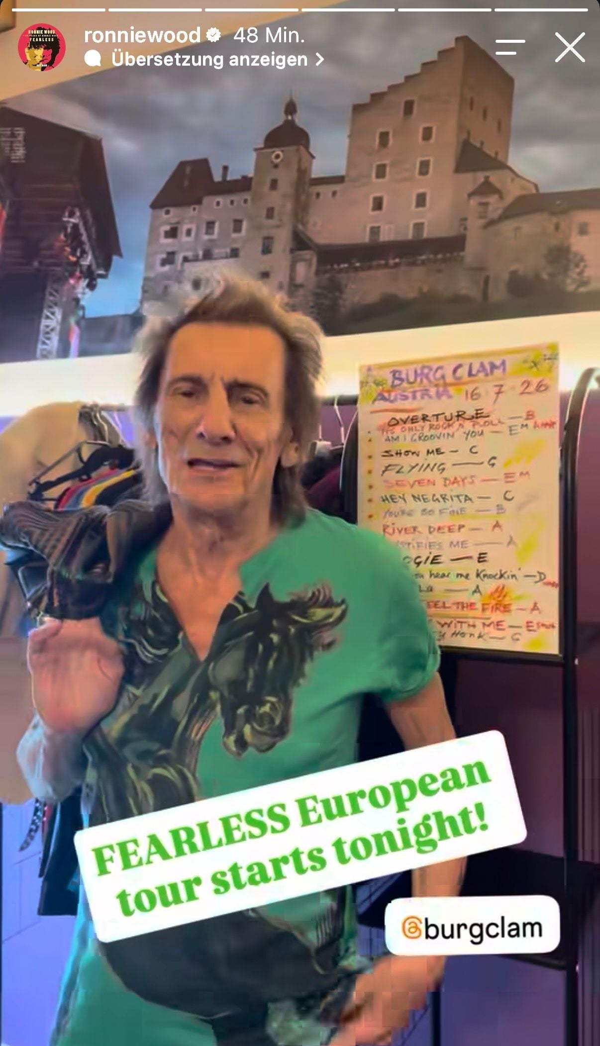 Ein Mann steht vor einem Plakat mit Setlist; Text: "FEARLESS European tour starts tonight!".