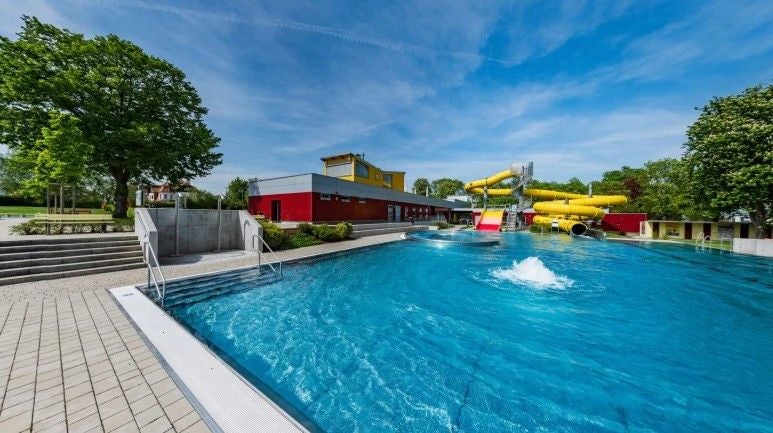 Freibad mit Wasserrutsche und modernem Gebäude im Hintergrund in St. Pölten.