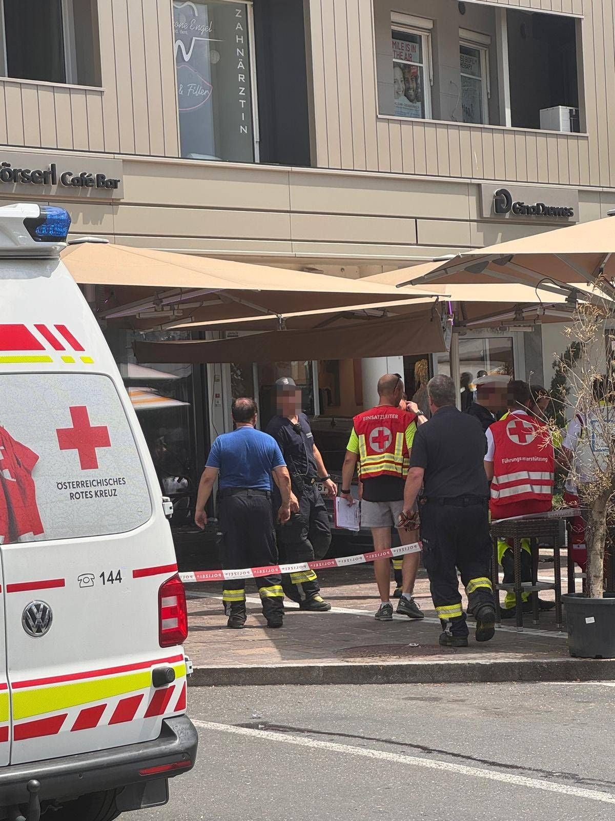Mehrere Einsatzkräfte des Roten Kreuzes und der Feuerwehr vor einem Café in Velden im Einsatz.