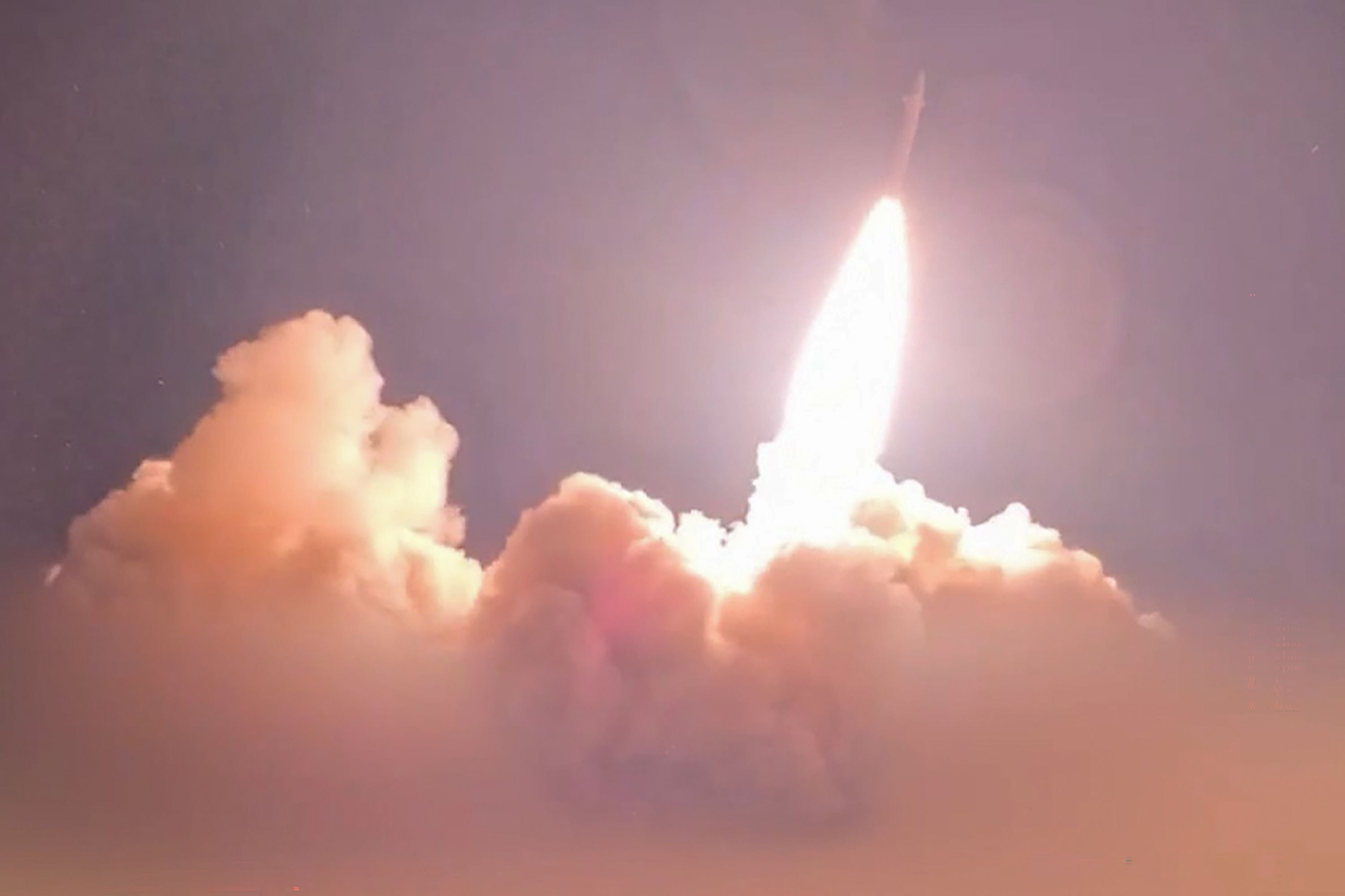 Eine Rakete wird nachts mit einer großen Flamme und Rauchwolke gestartet.