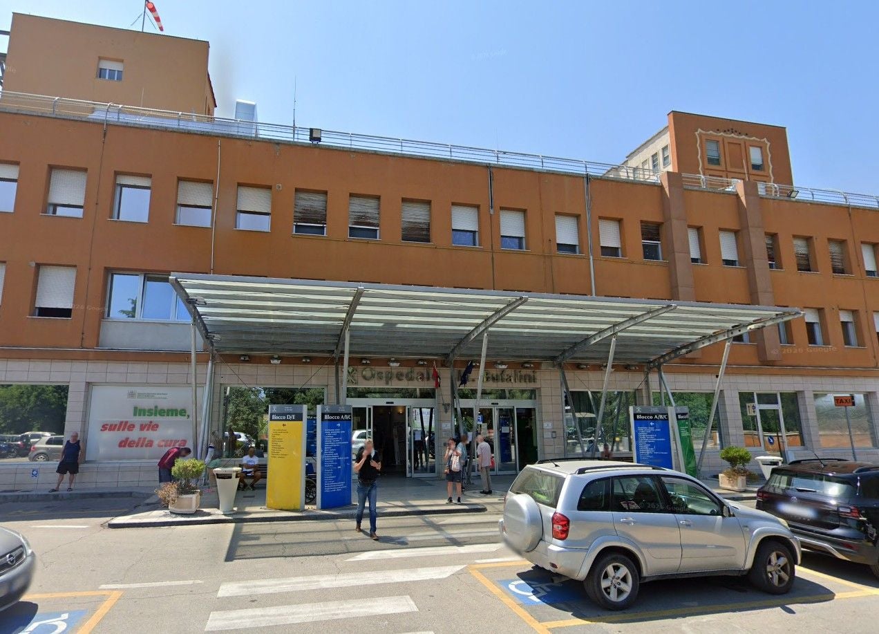 Haupteingang eines Krankenhauses mit Glasvordach und mehreren Menschen davor.