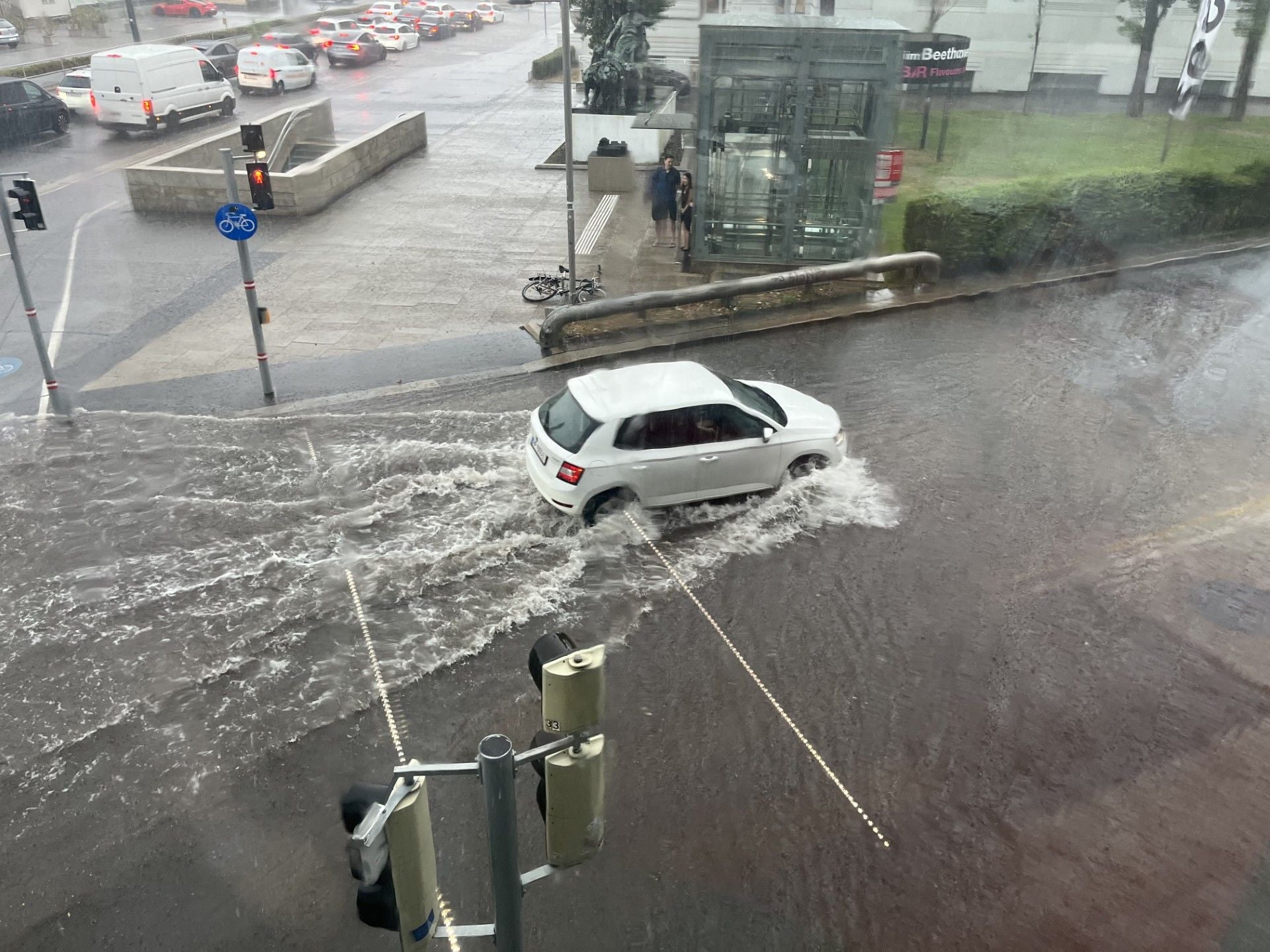 Ein Auto fährt durch eine überflutete Straße bei starkem Regen. (Archivbild)