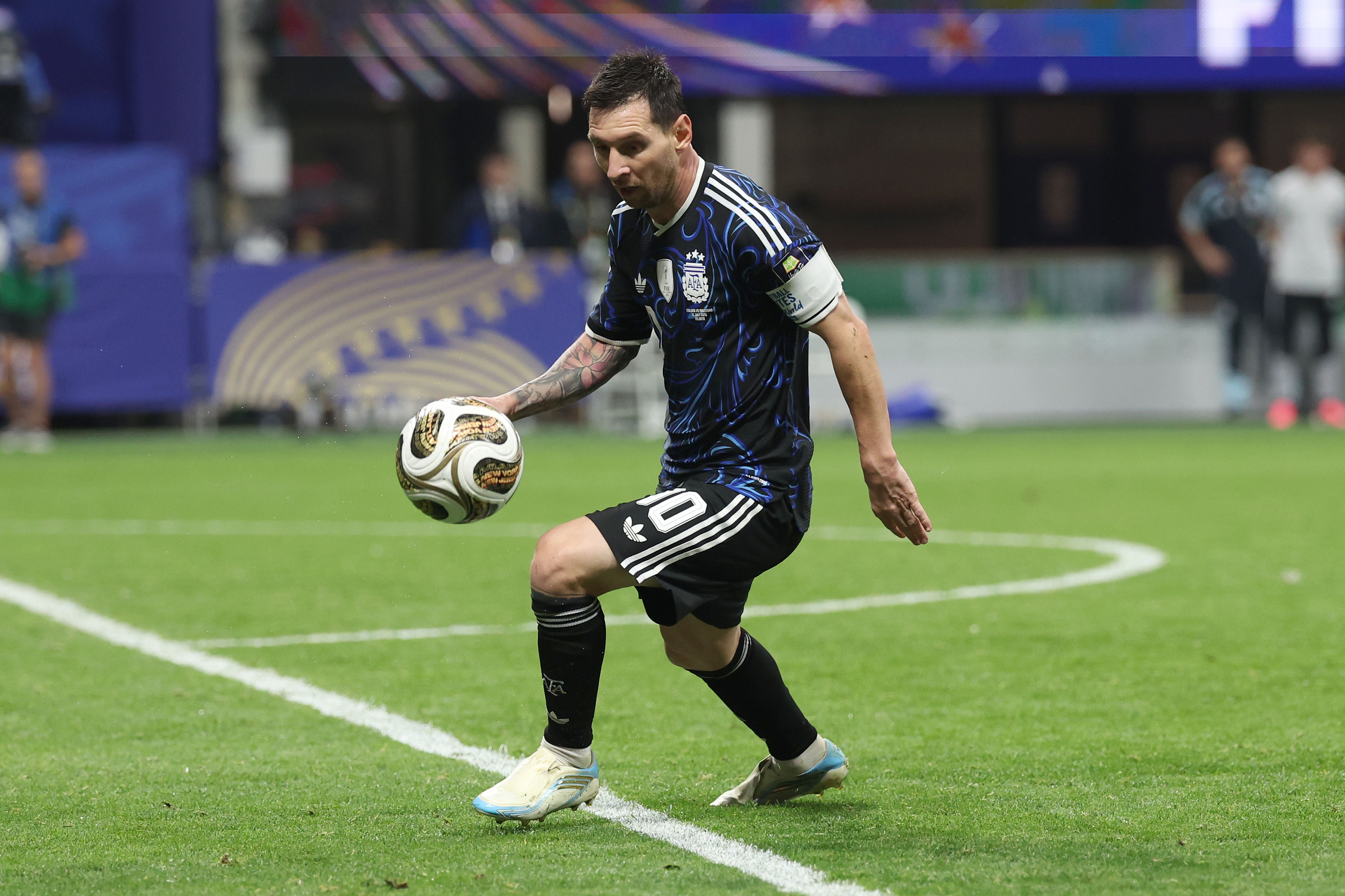 Ein Fußballspieler im schwarzen Argentinien-Trikot kontrolliert den Ball auf dem Spielfeld.
